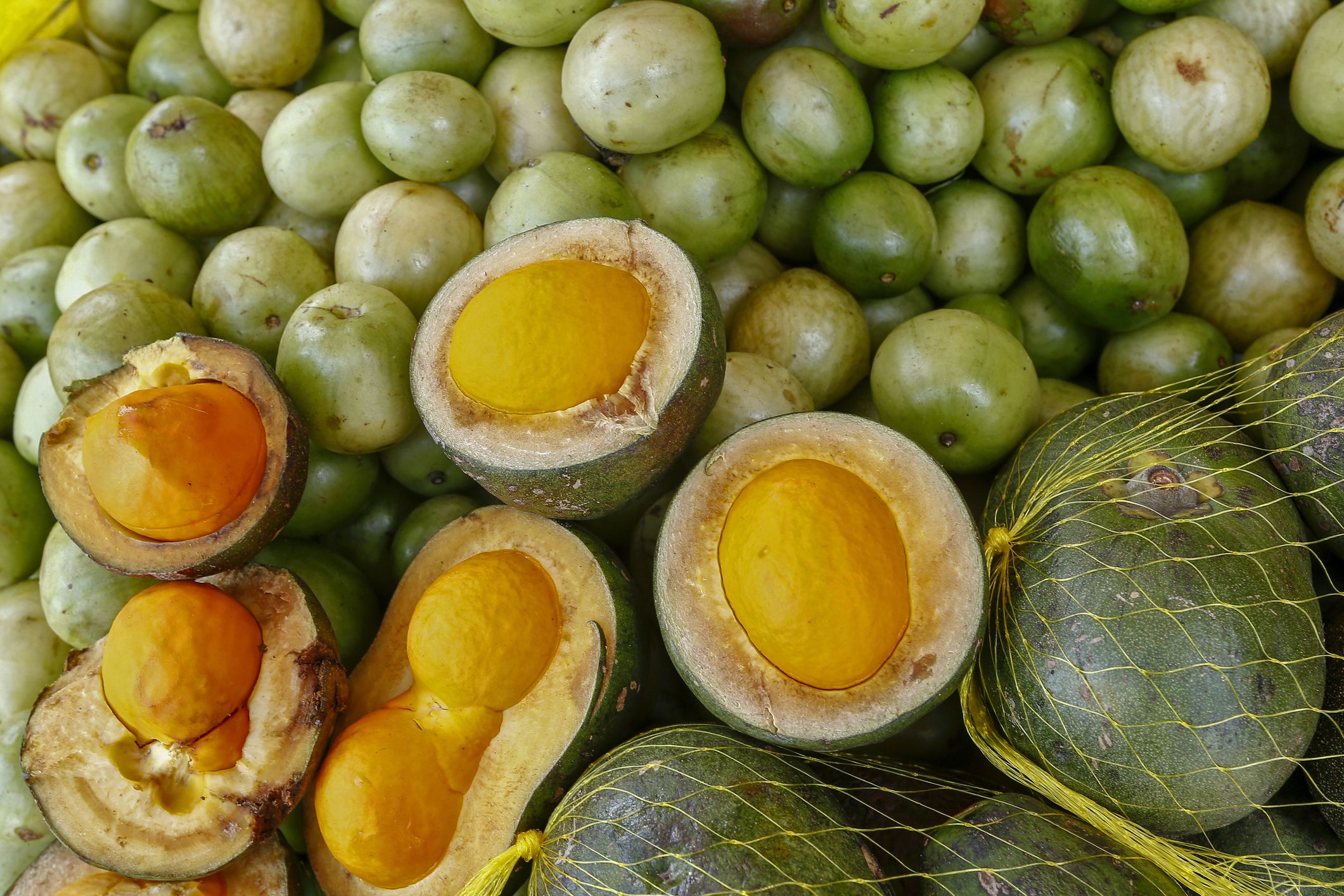 Pequi, Brazilian Cerrado fruit, on lot of umbu in street market stall. Sao Paulo Brazil
