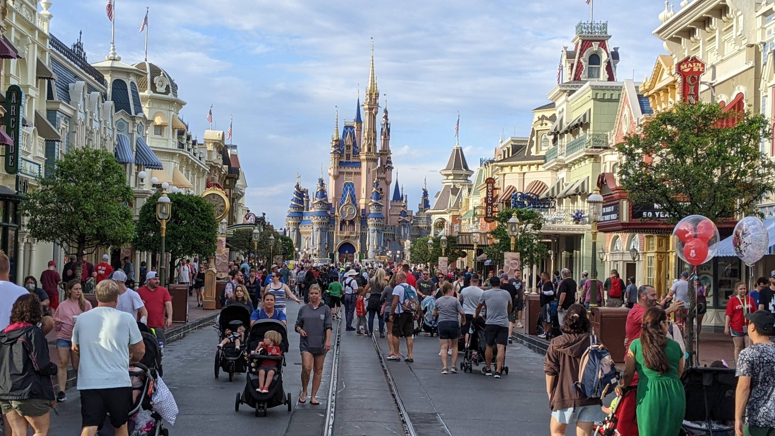 Visitors on Main Street, Magic Kingdom, Walt Disney World, Orlando, Florida. Cinderella's Castle at rear is decorated for the 50th anniversary of the parks's opening.