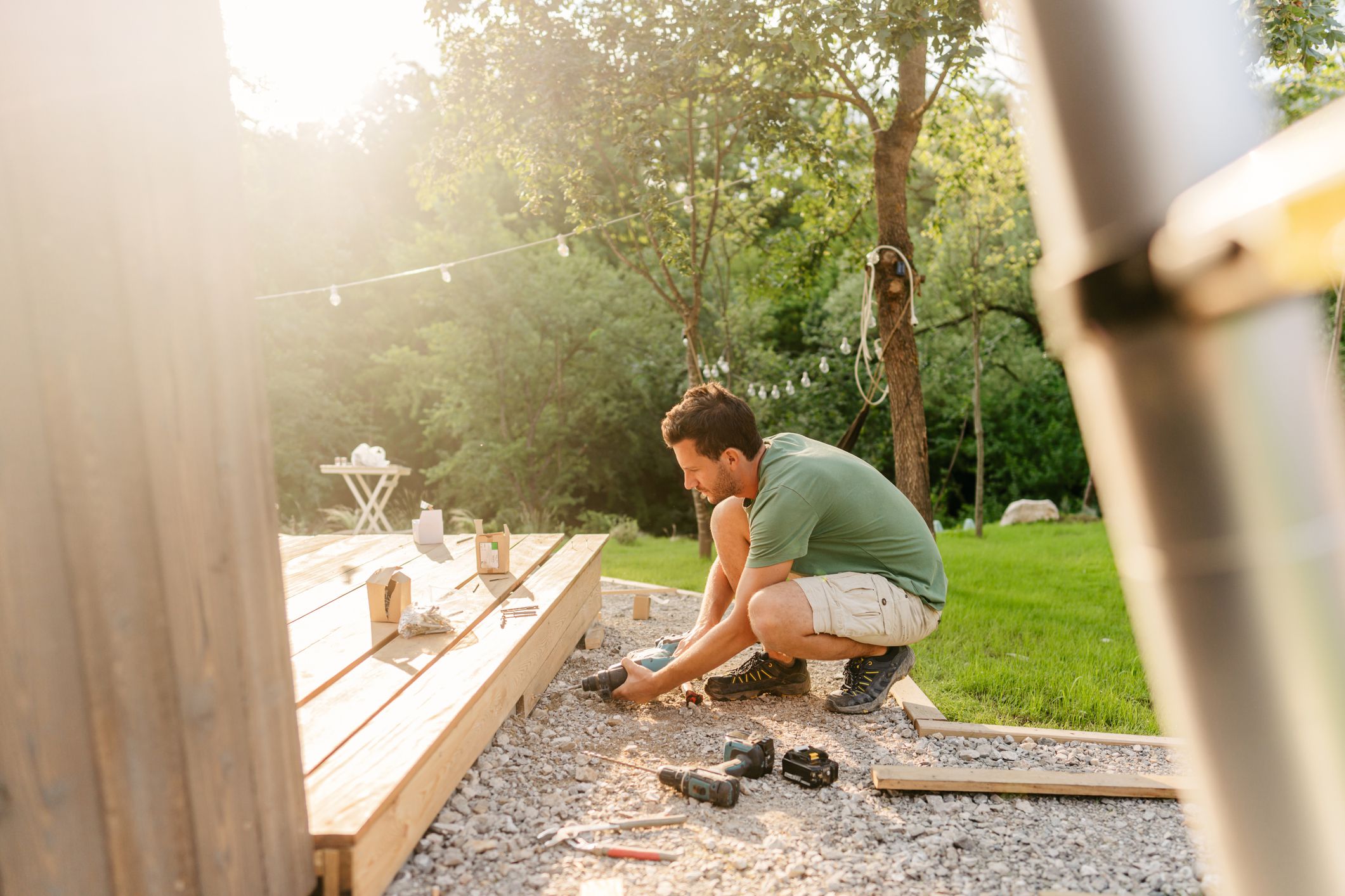 Photo of a carpenter attaching decking boards to a deck of a house.