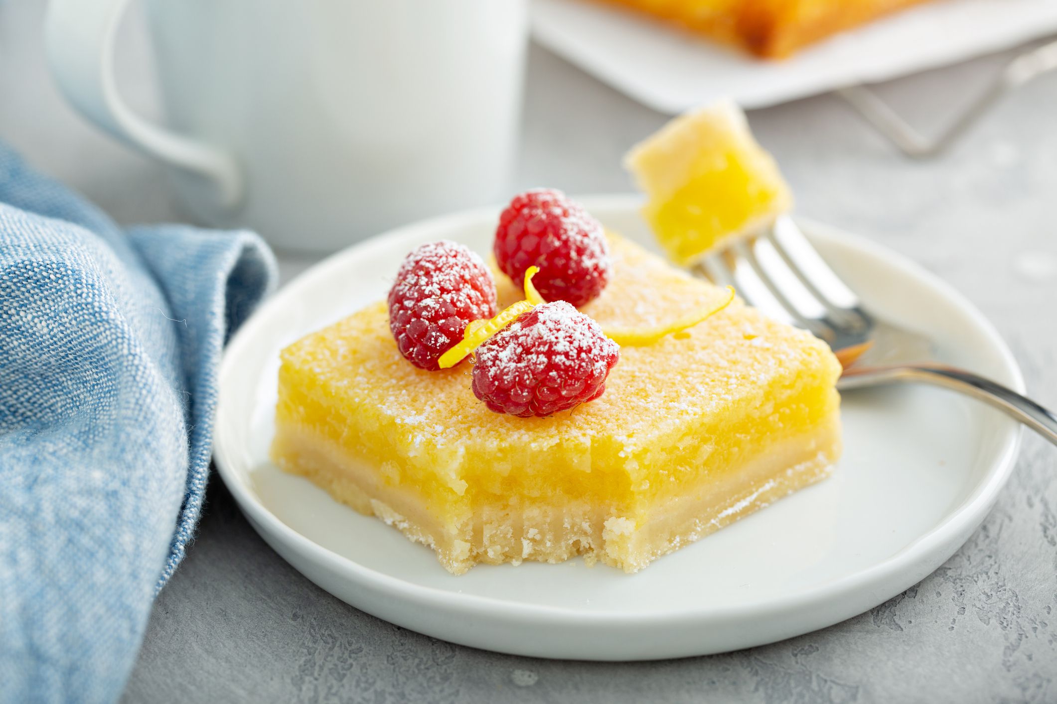 Homemade lemon bars topped with powdered sugar and fresh raspberries