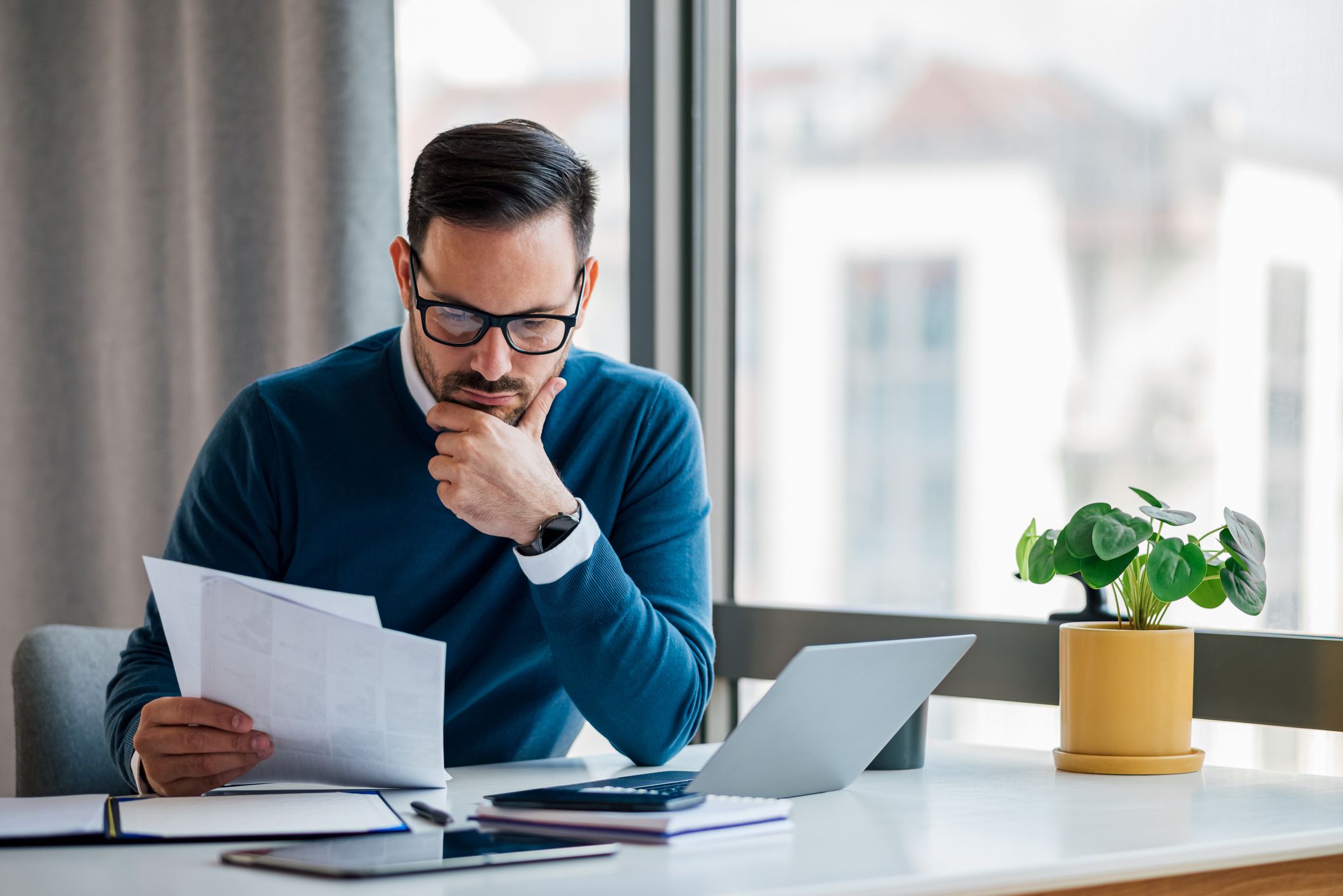 Focused entrepreneur, lost in his thoughts at the office, checking the business plans of the company.