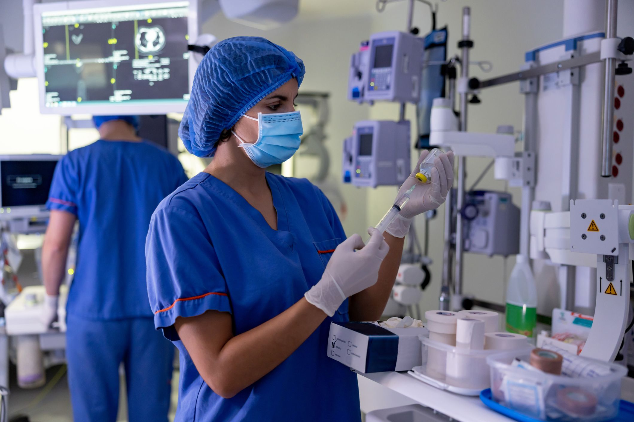 Surgical nurse filling a syringe with some medicine in the operating room