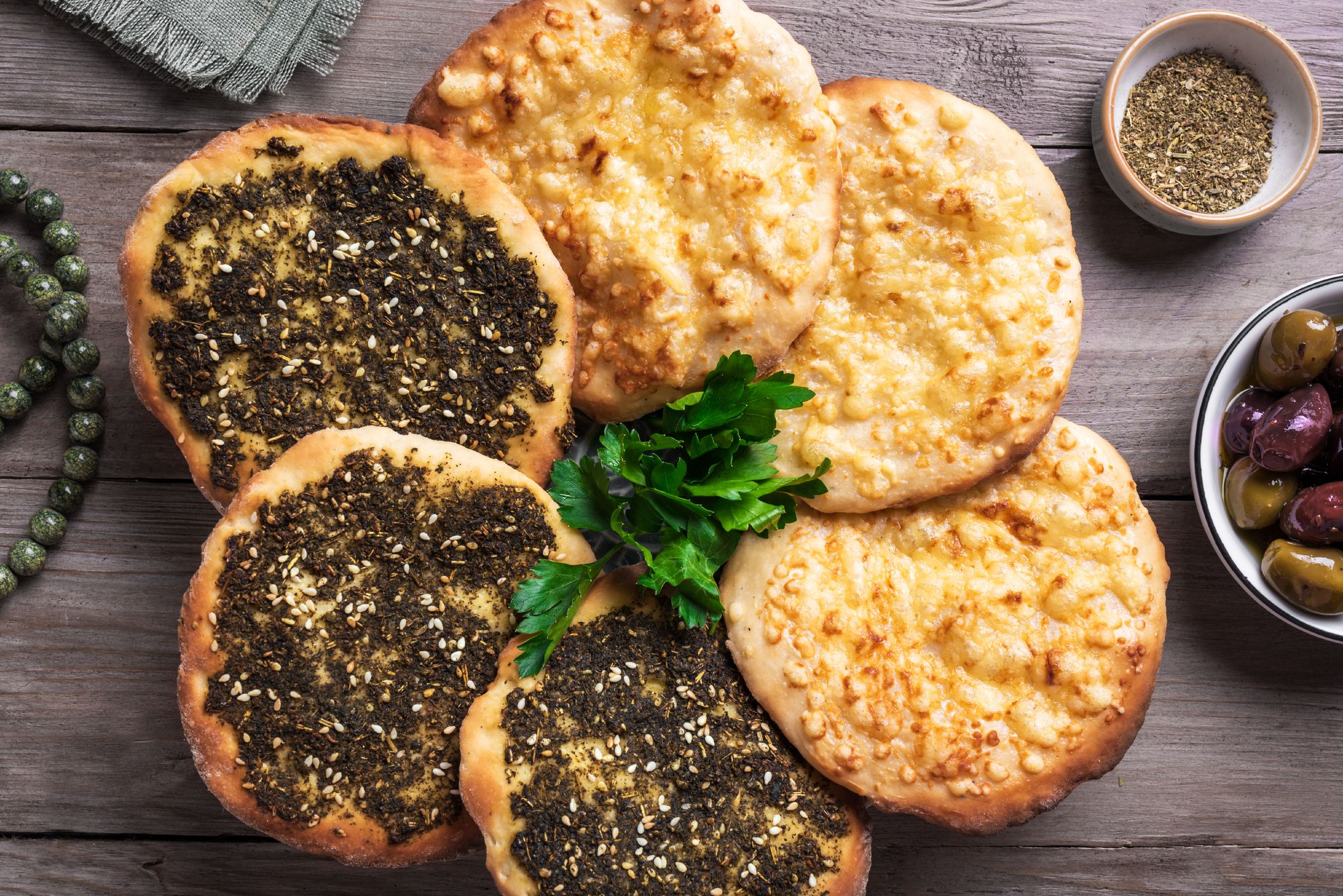 Manakeesh, arabic pizza, flat bread topped with zaatar spices and cheese. Homemade mediterranean flat bread manakish on wooden table.
