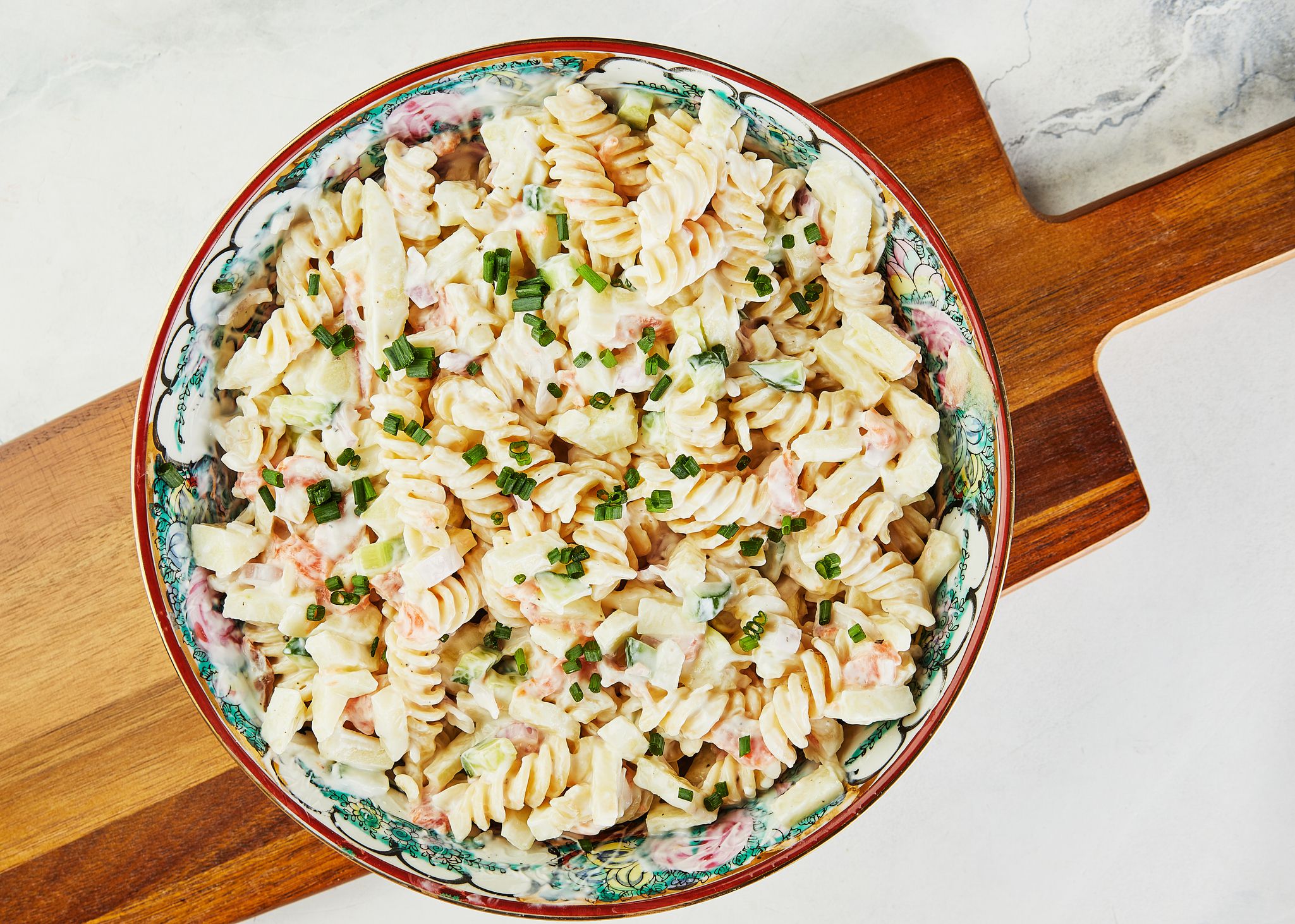 Fusilli salad with shrimp and green onions in colored bowl. Flat lay.
