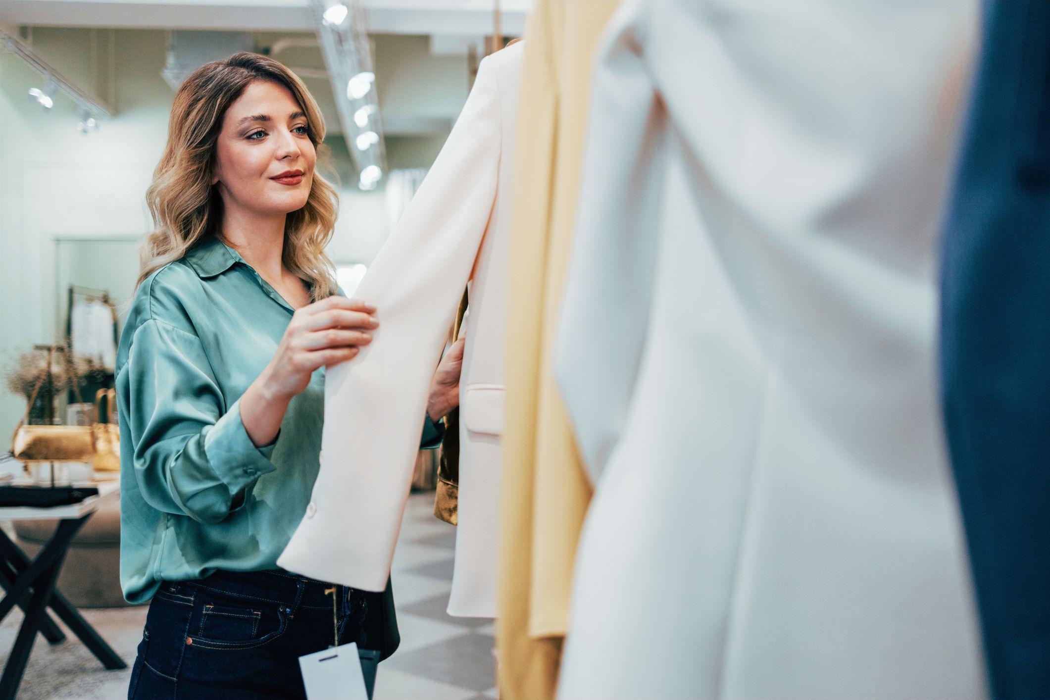 A female fashion designer thoughtfully examines various fabric options, weighing choices in a well-lit boutique. Her focus and professionalism highlight her expertise in fashion design.