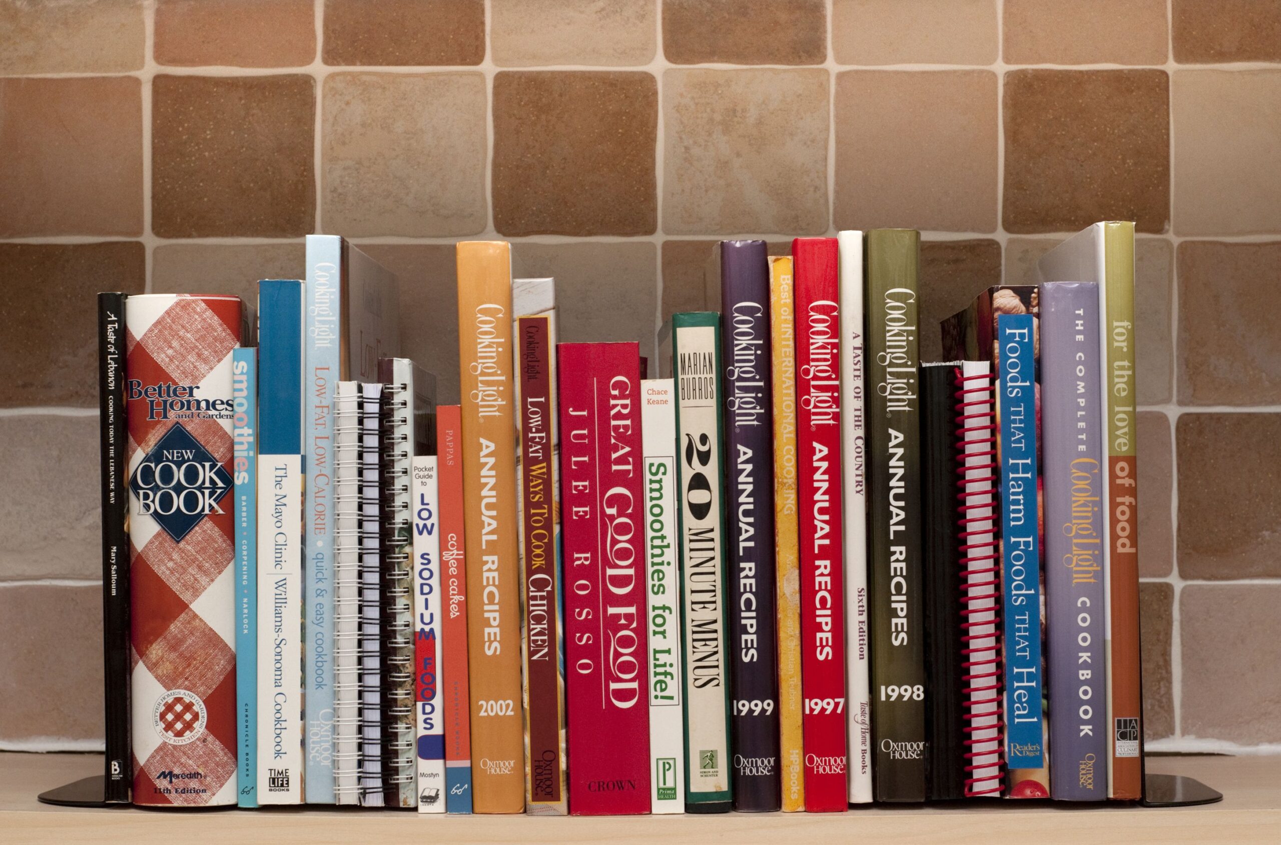 London, England-April 2, 2011. Cookbooks on kitchen shelf. Cook books include one by Julee Russo a Better Homes Cook book and many cookbooks published by Cooking Light.
