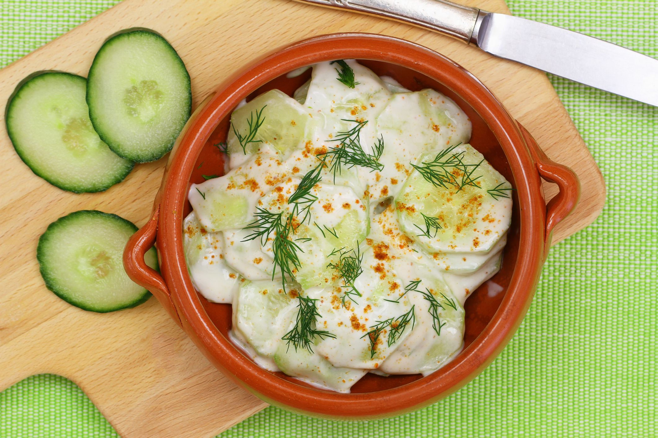 Cucumber salad with sour cream and fresh dill in clay bowl