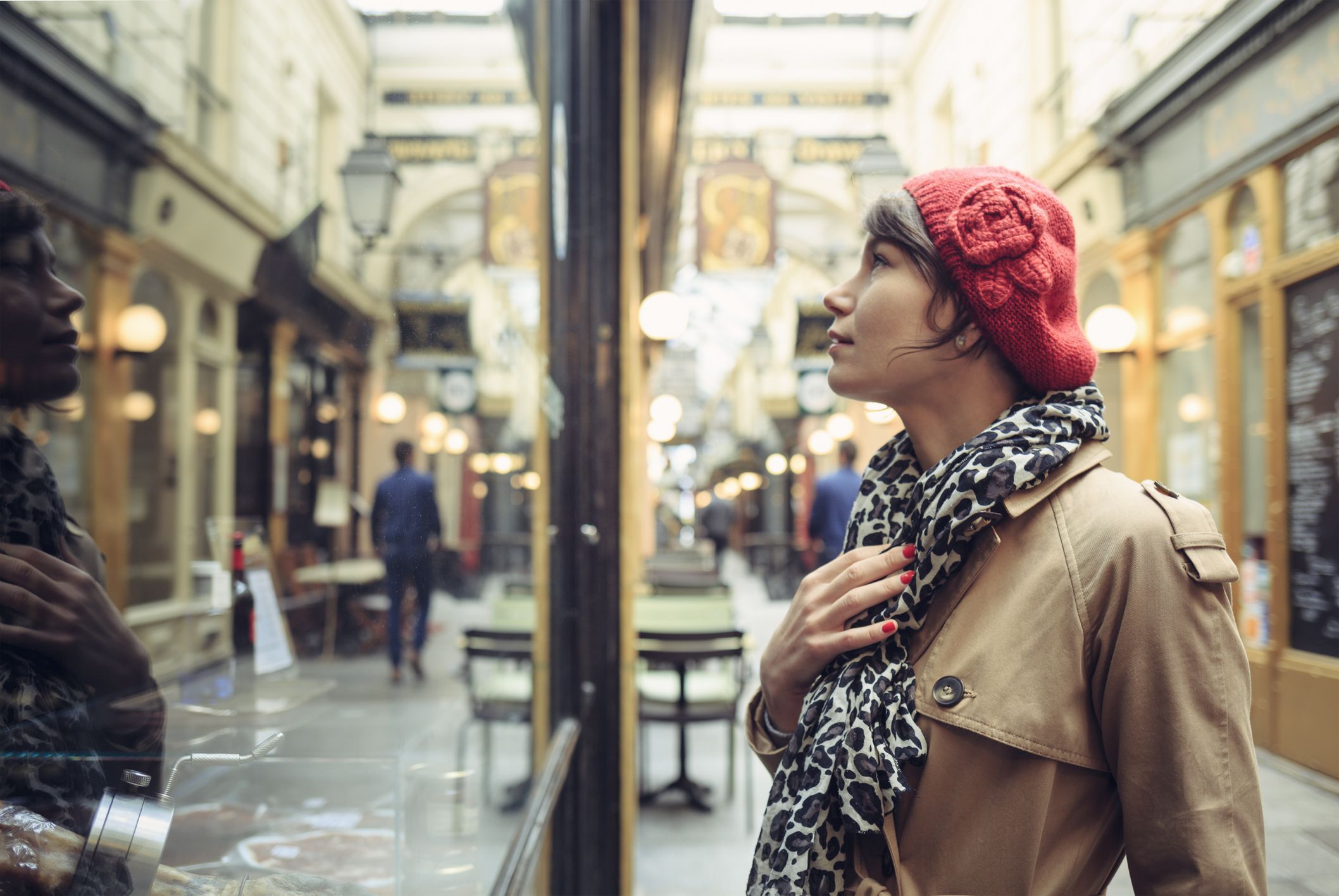 Woman looking into window of traditional store in Paris, France.
