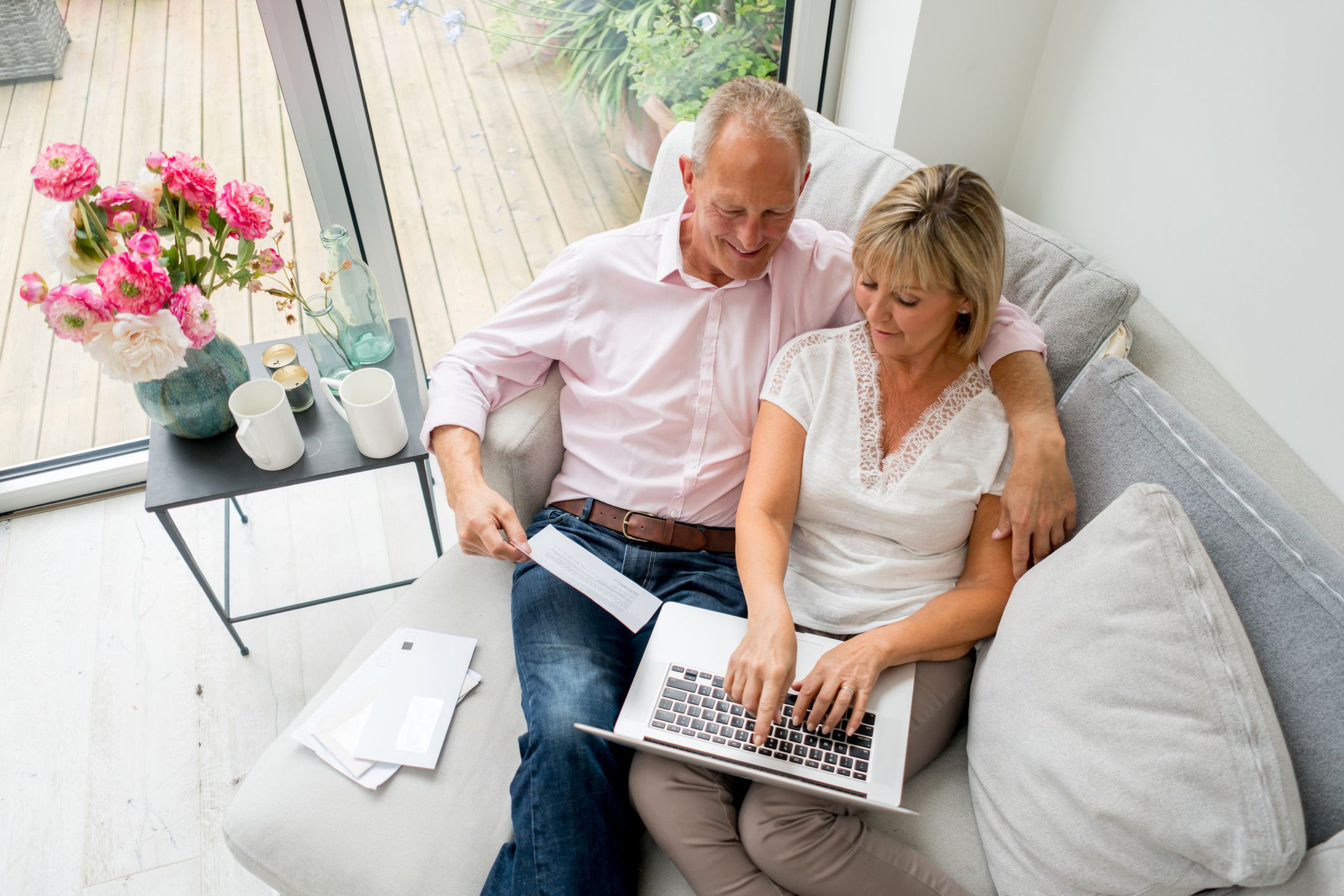 Happy senior couple paying bills online at home from a laptop computer - technology concepts