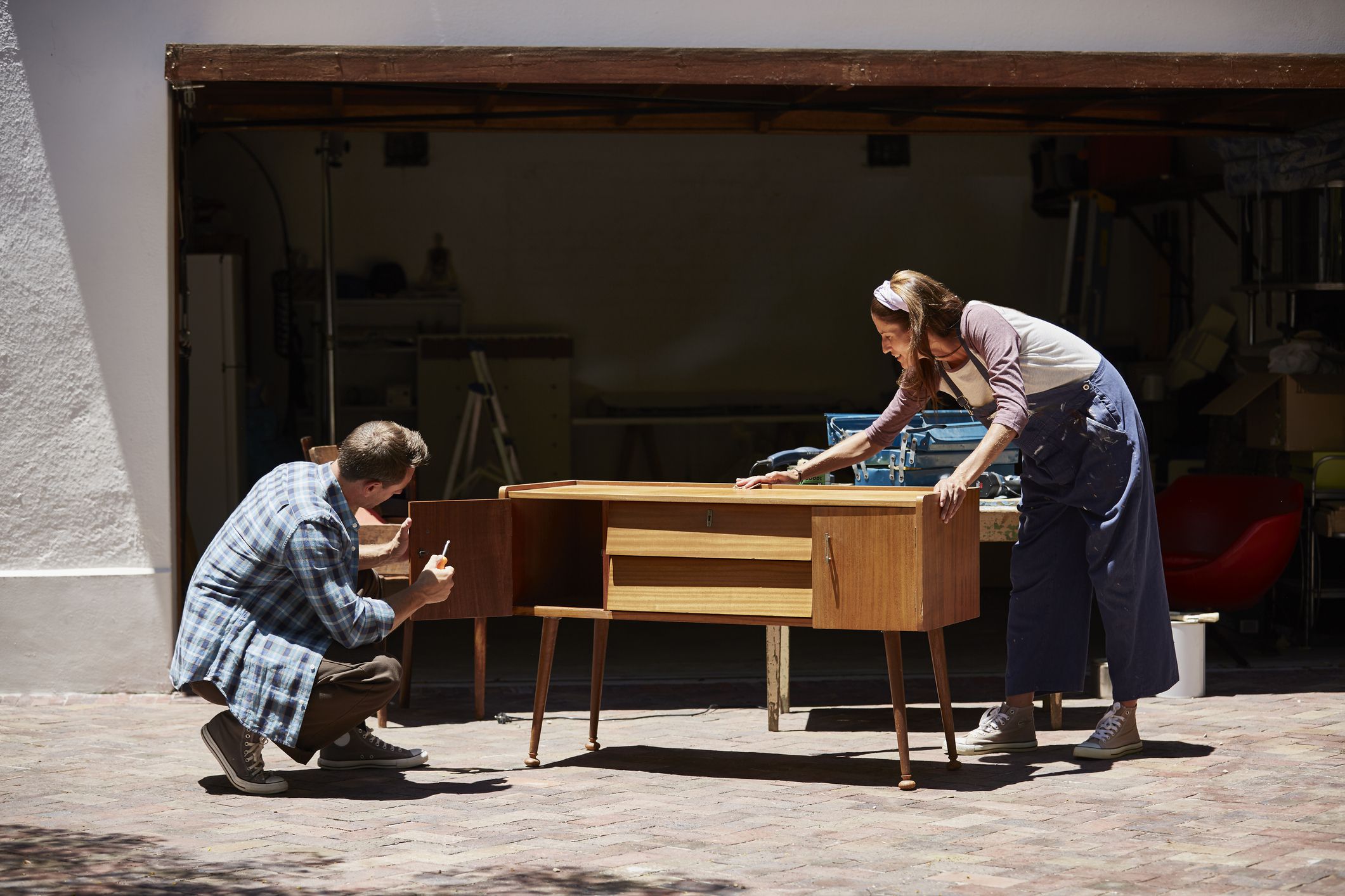 Full length of couple refinishing furniture outside house