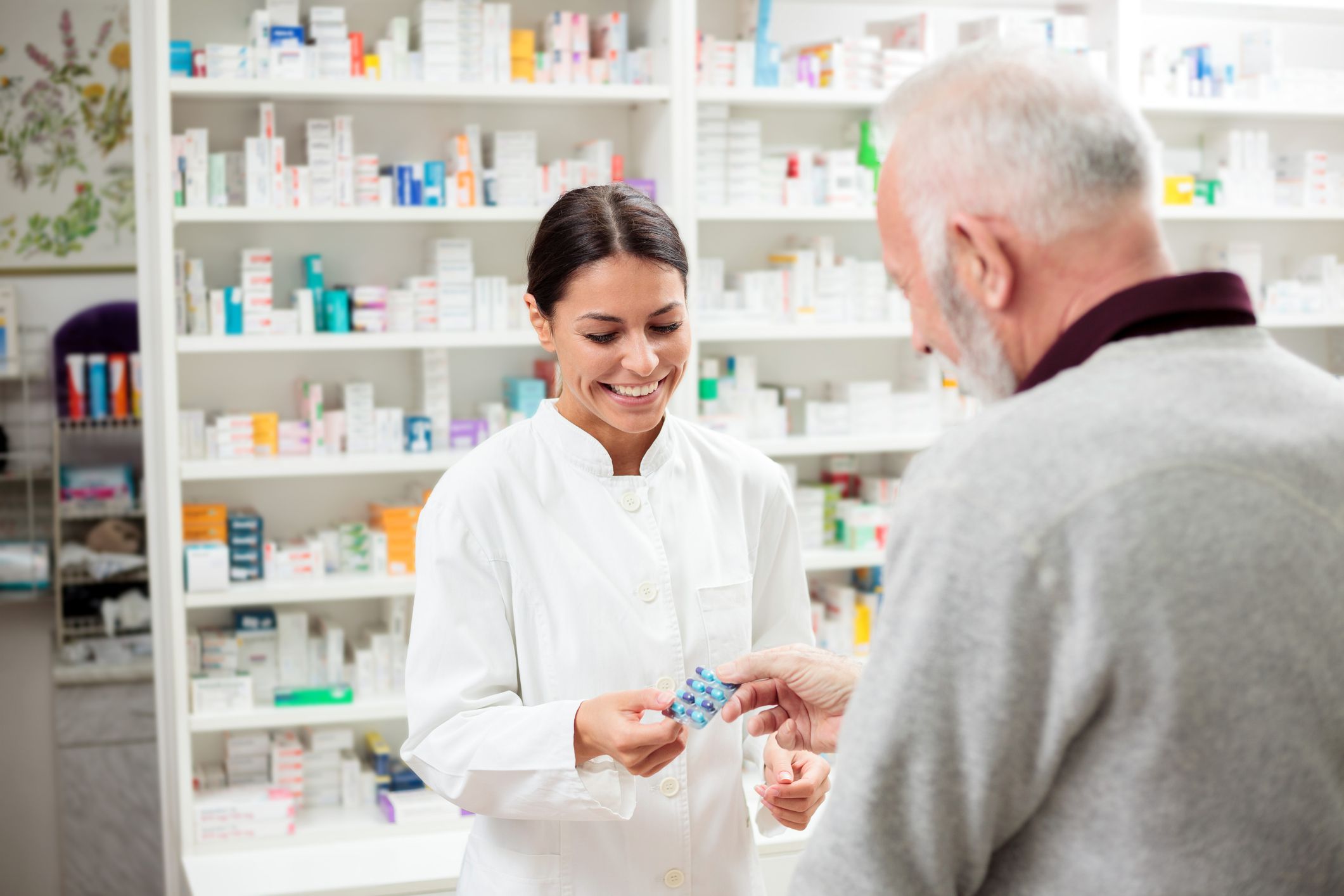Medicine, pharmaceutics, health care and people concept - Happy female pharmacist giving medications to senior male customer