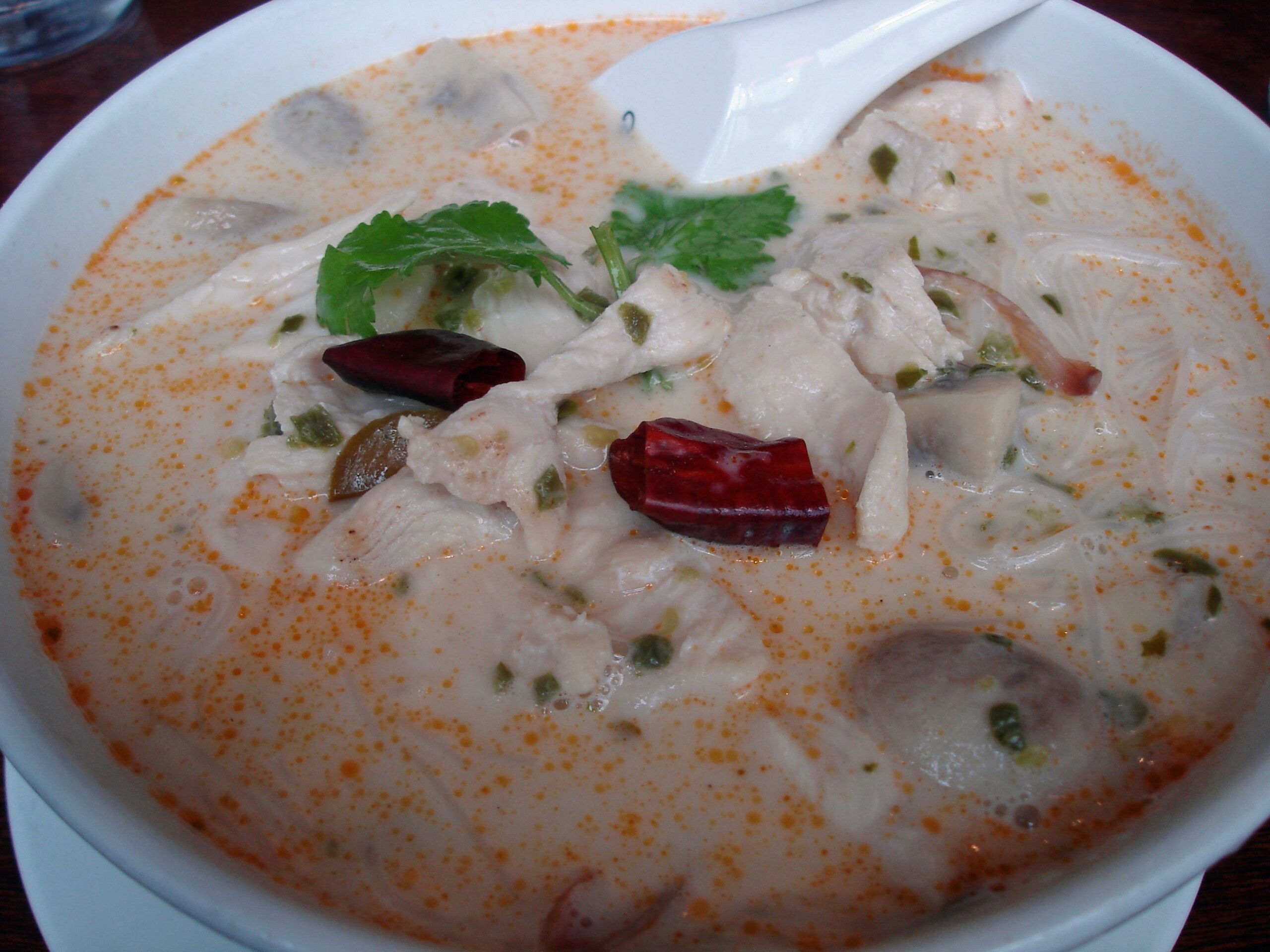 a bowl of thai tom kha soup with coconut milk