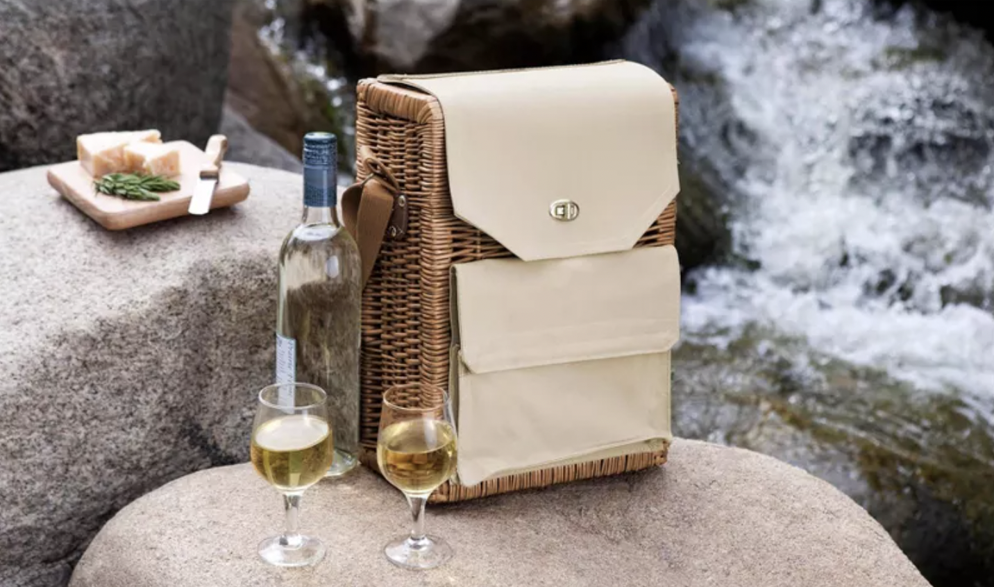 Wine and cheese basket displayed on a rock with two glasses of wine poured
