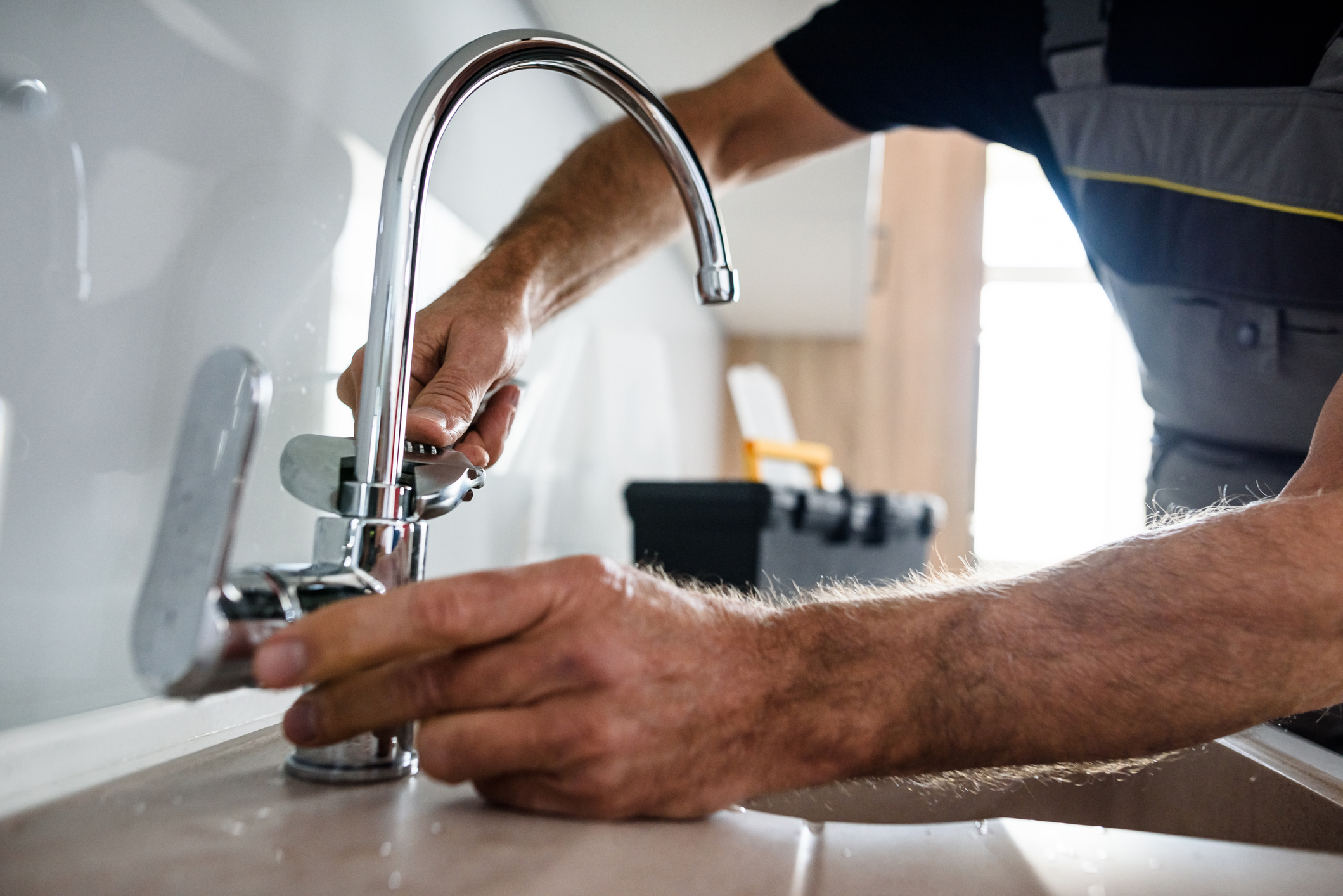 Closeup of Man Installing a New Kitchen Faucet in a Home