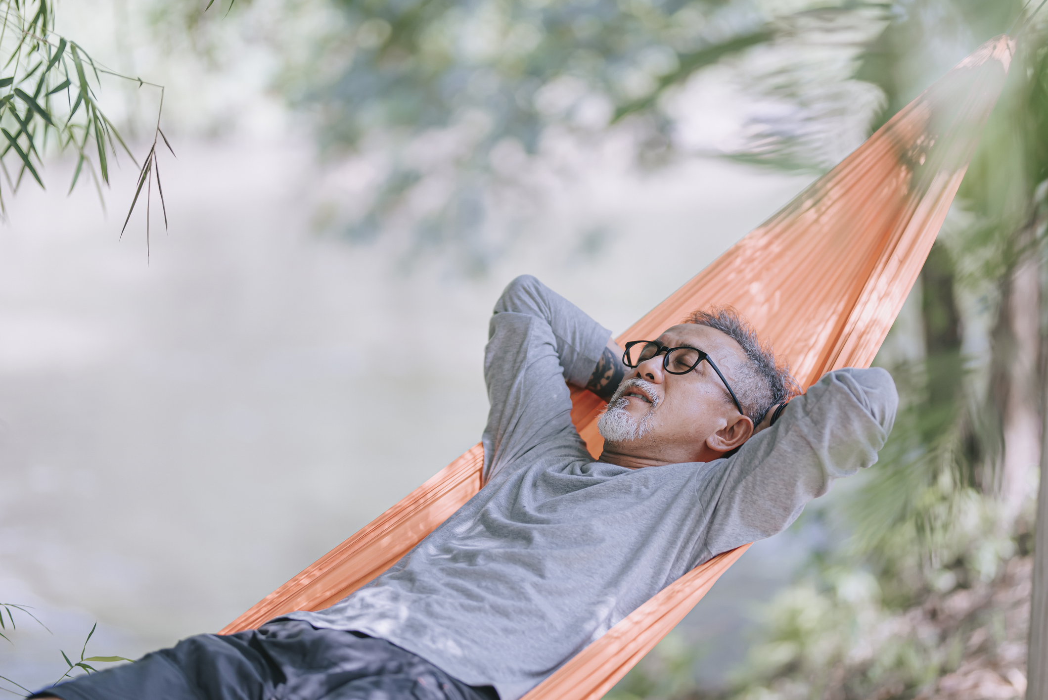 Asian Man Taking a Nap on a Hammock Outside