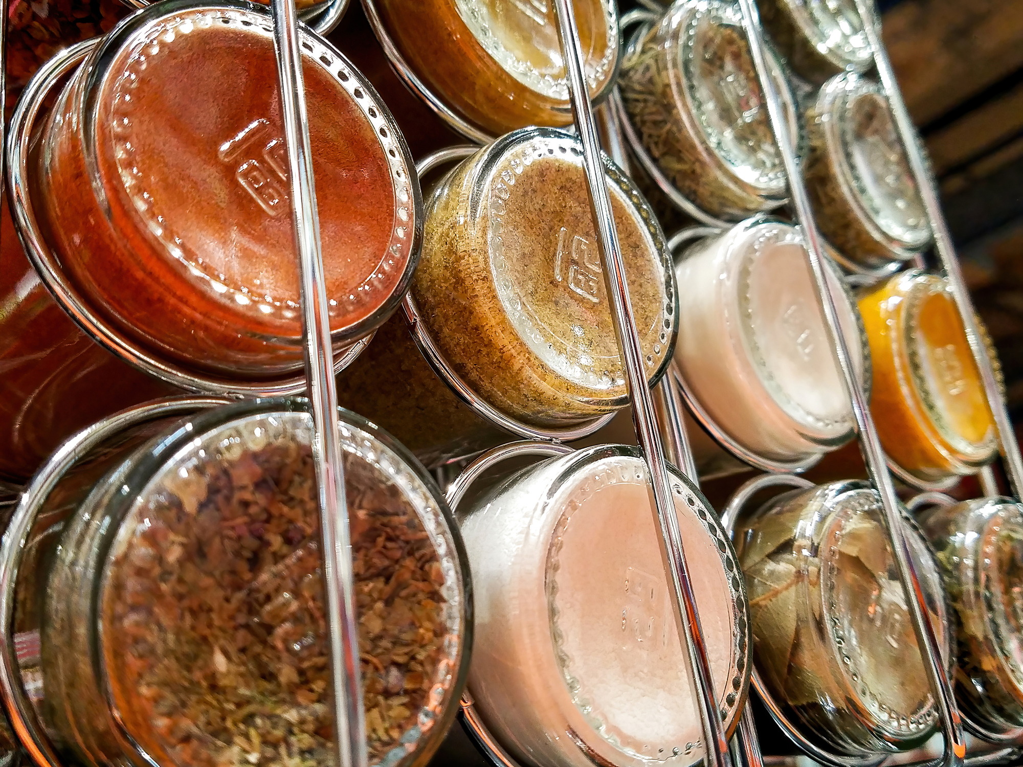 Closeup of Backs of Glass Bottles Filled With Spices on a Spice Rack