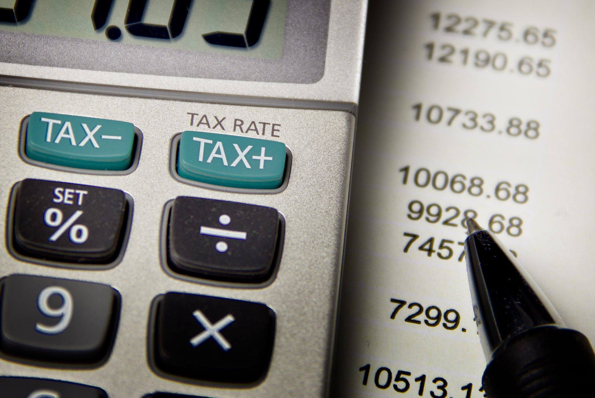 Closeup of 'Tax Rate' Button on Calculator With Pen, Sheet of Expenses Underneath