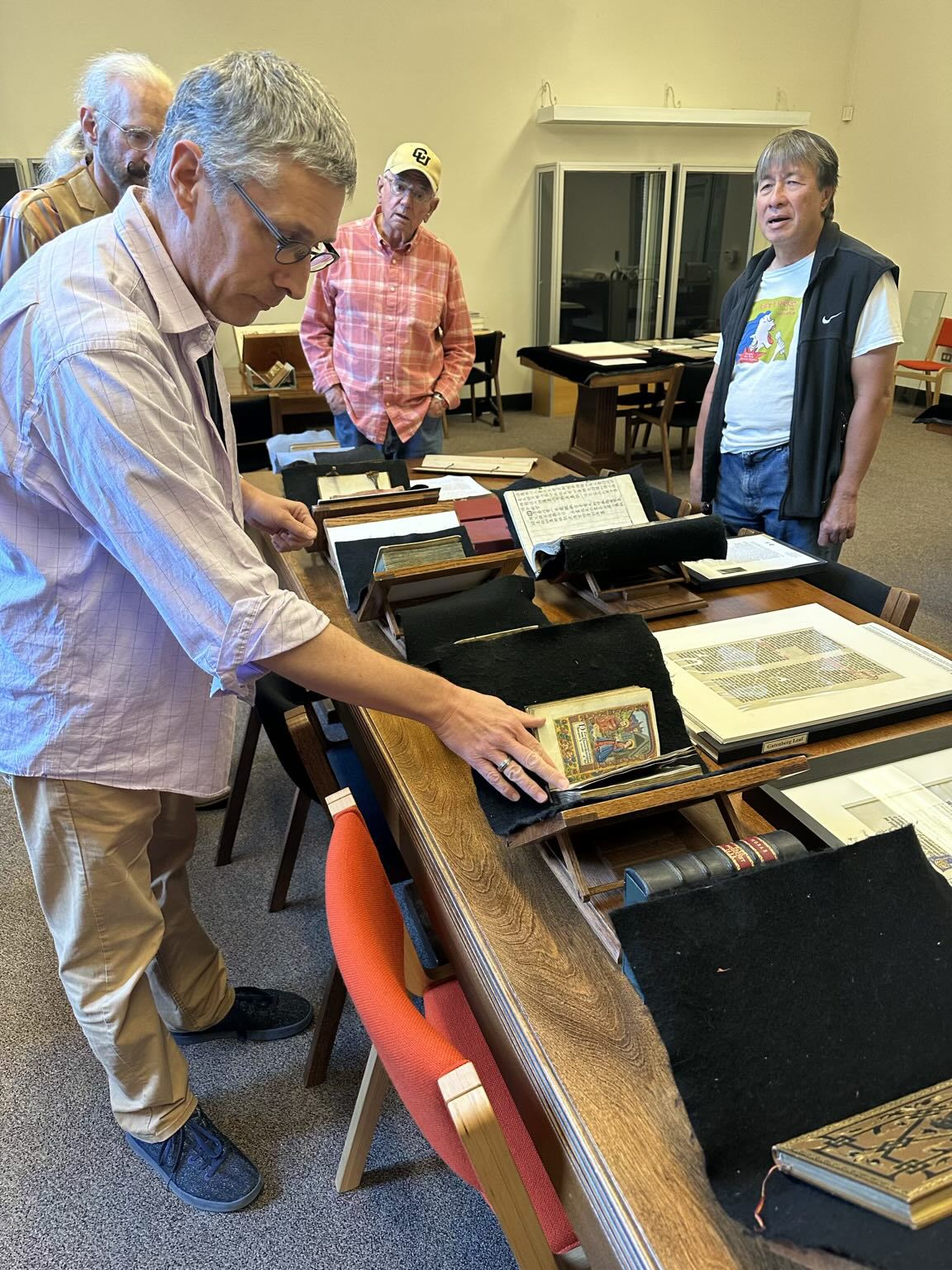 Four Senior Men Looking Through Old Books Together at the University of Colorado Boulder