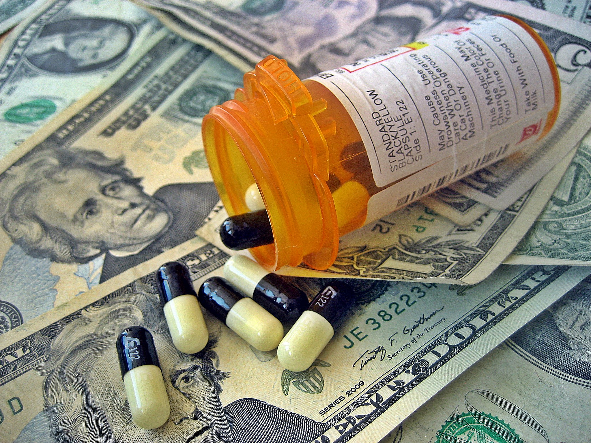 Opened Bottle of Prescription Pills Spilled on U.S. Dollar Bills