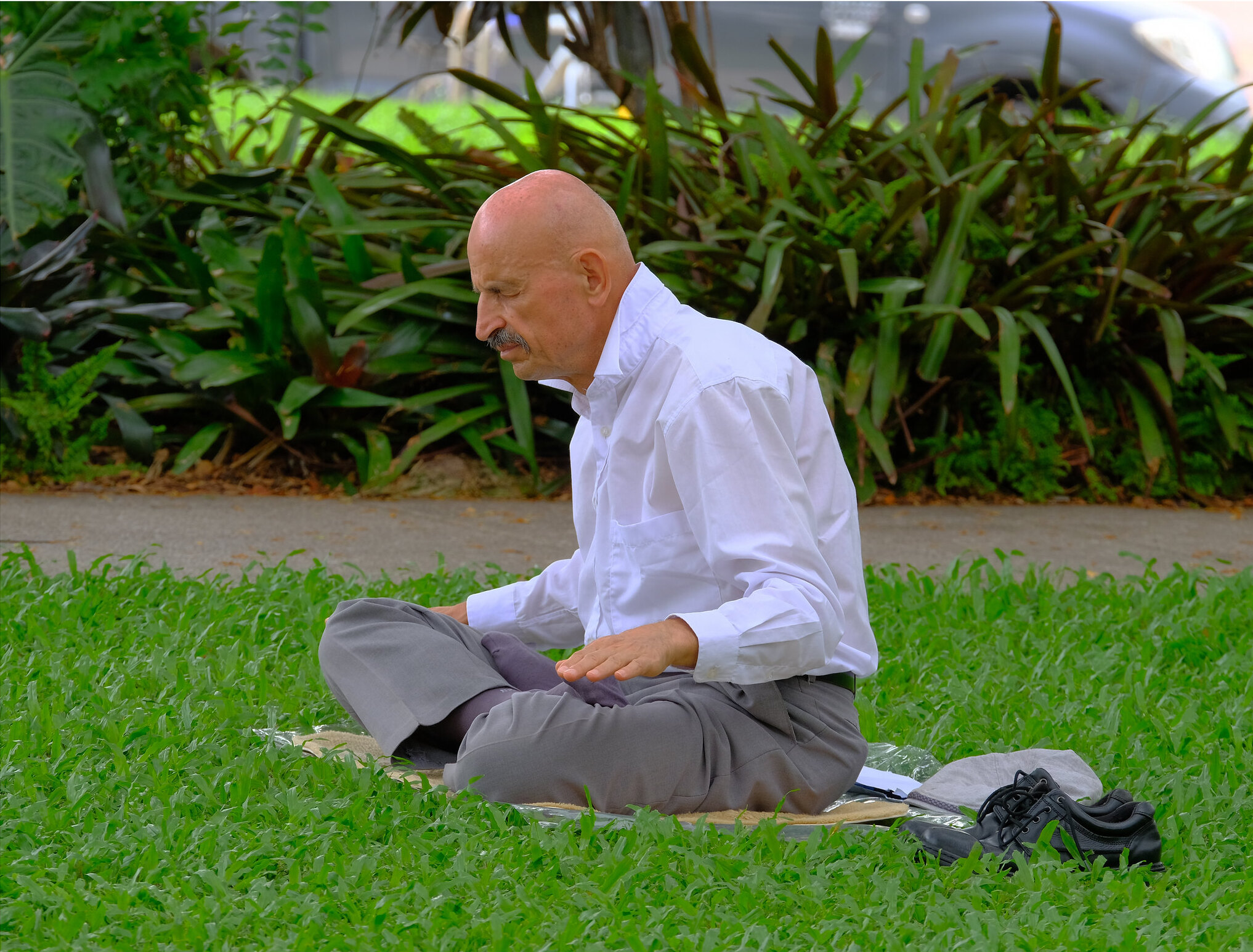 Senior Man Deep in Meditation at a Park, While Wearing Office Clothing