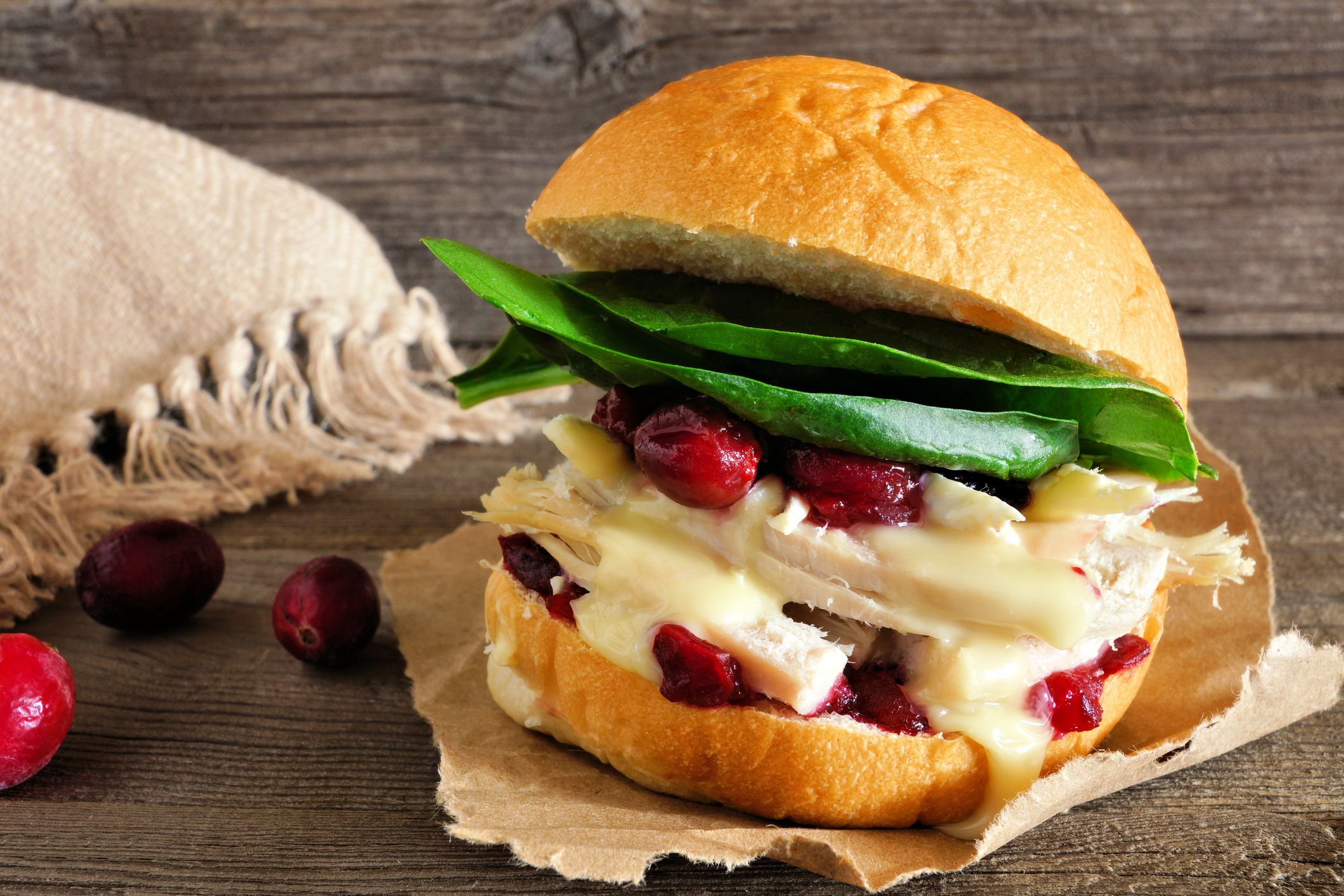 Roasted turkey sandwich with cranberry sauce and cheese. Close up with a rustic wood background.