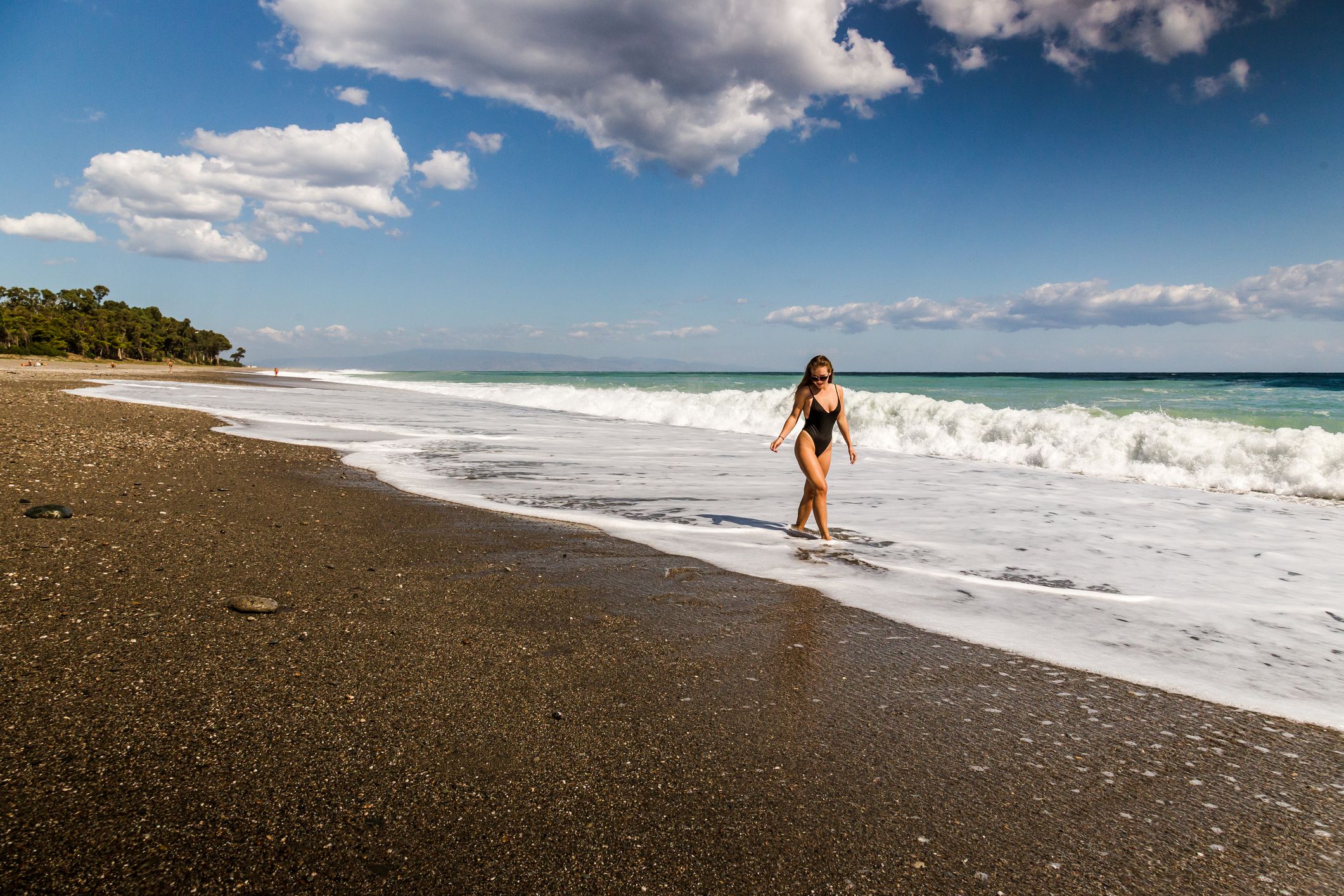 Woman enjoying waves in Spiaggia San Marco near Taormina, Sicily