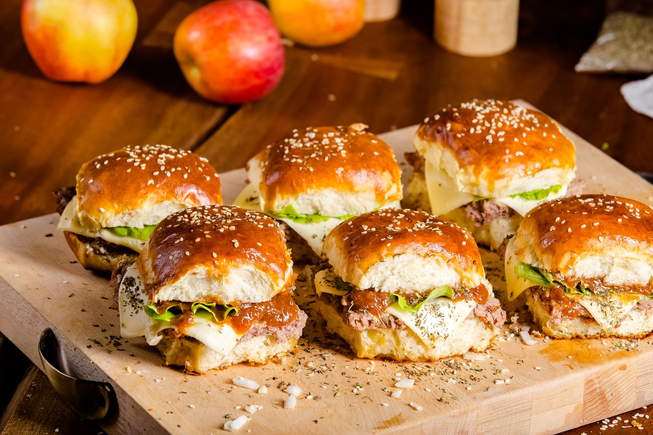 new large hamburger burger with meat, bacon, sausage, lettuce, champignons, pineapple and tomatoes, sauce and cheese standing on a wooden cutting kitchen board, on the table