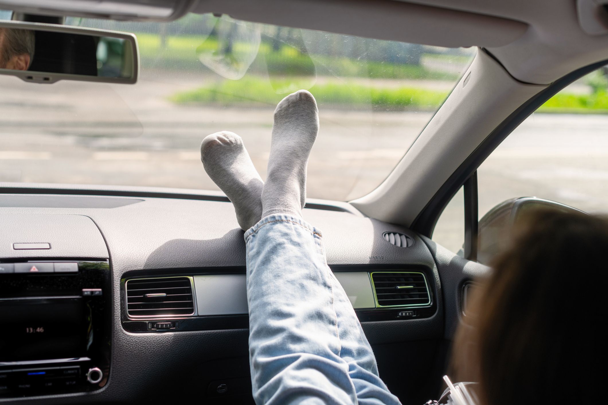 Woman passenger, legs in a jeans and socks on car dashboard while travel on the highway. Freedom concept.