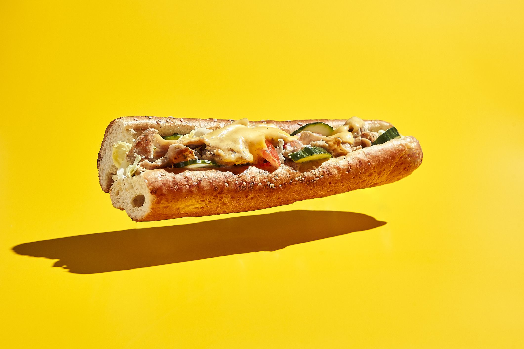 American fast food minimal concept. Flying chicken sandwich on yellow background. Chicago cheese steak