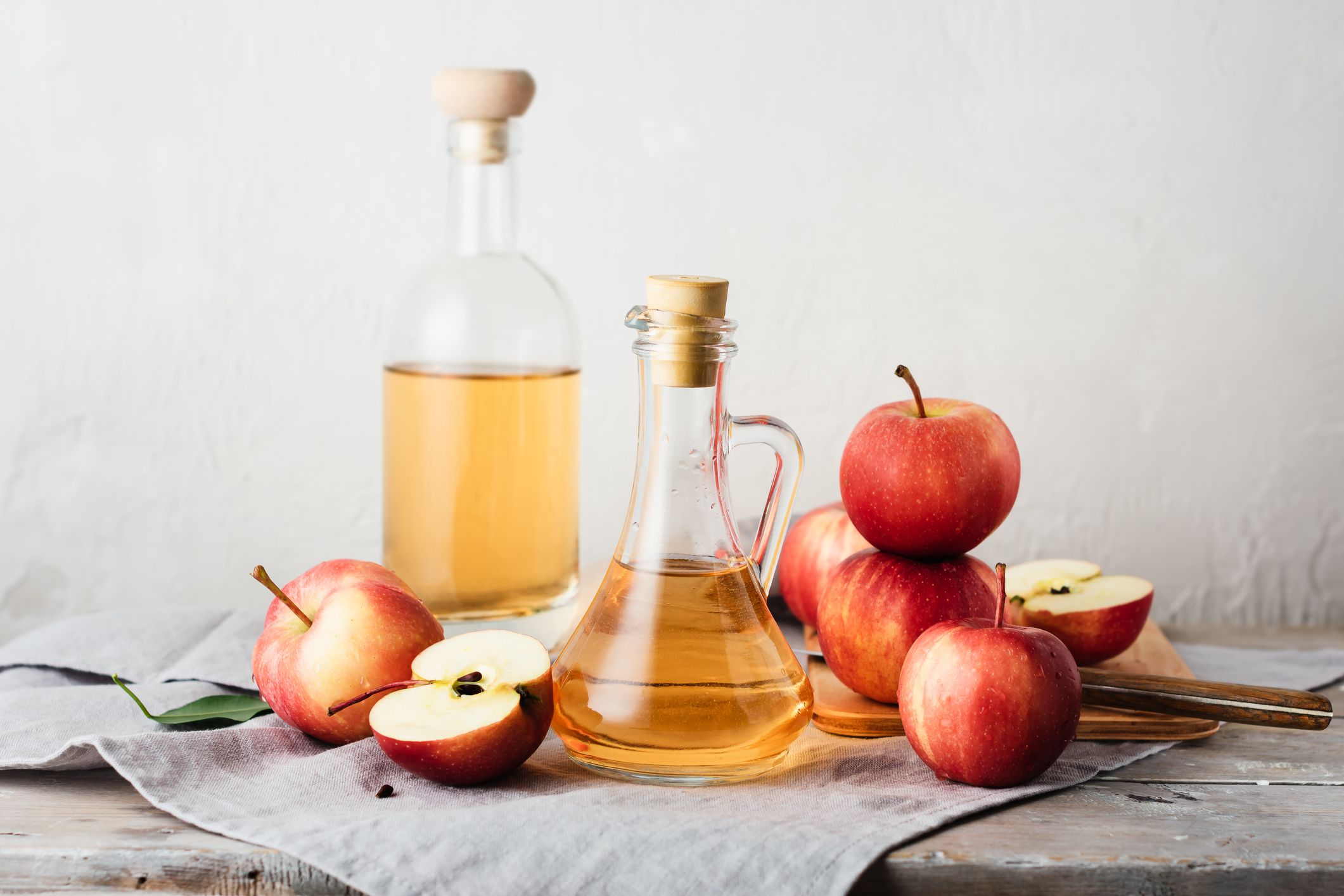Apple cider vinegar and fresh red apples.