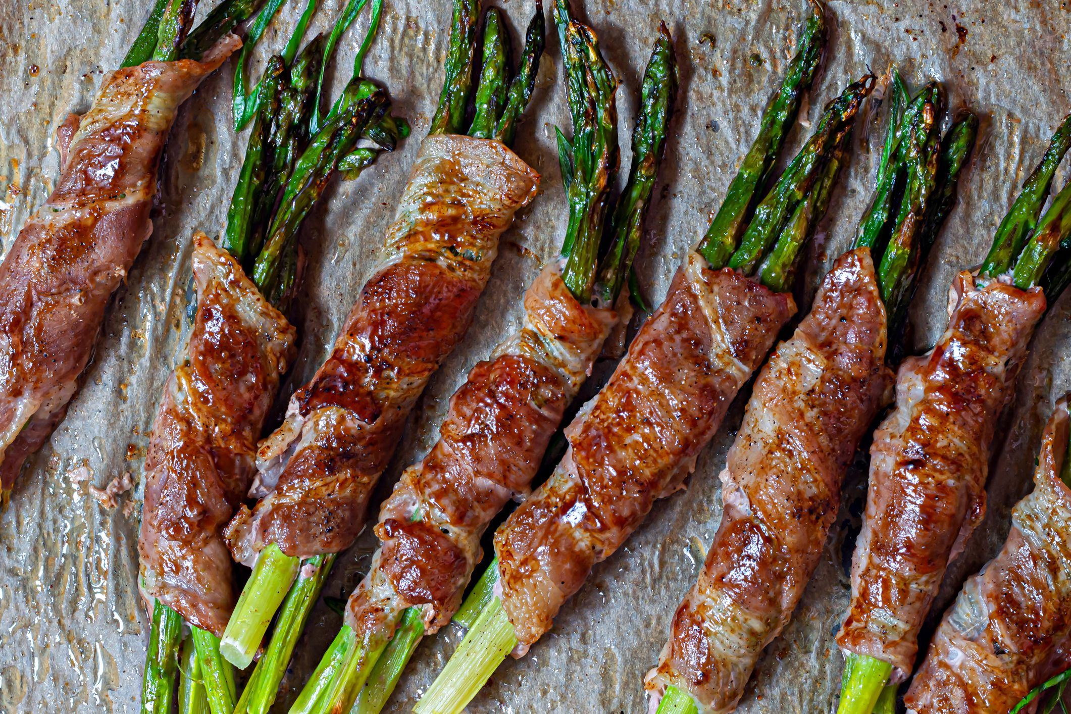 Baked green asparagus wrapped in crispy bacon. Light snack, side dish (garnish).