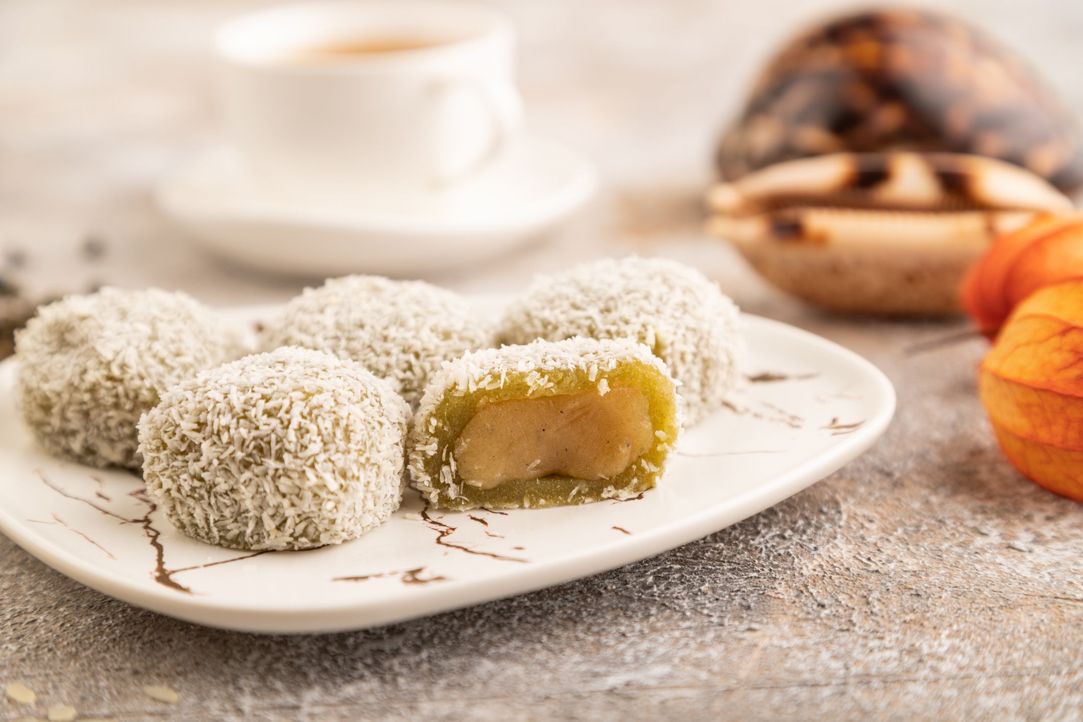 Japanese rice sweet buns mochi filled with pandan jam and cup of green tea on brown concrete background. side view, close up, selective focus.