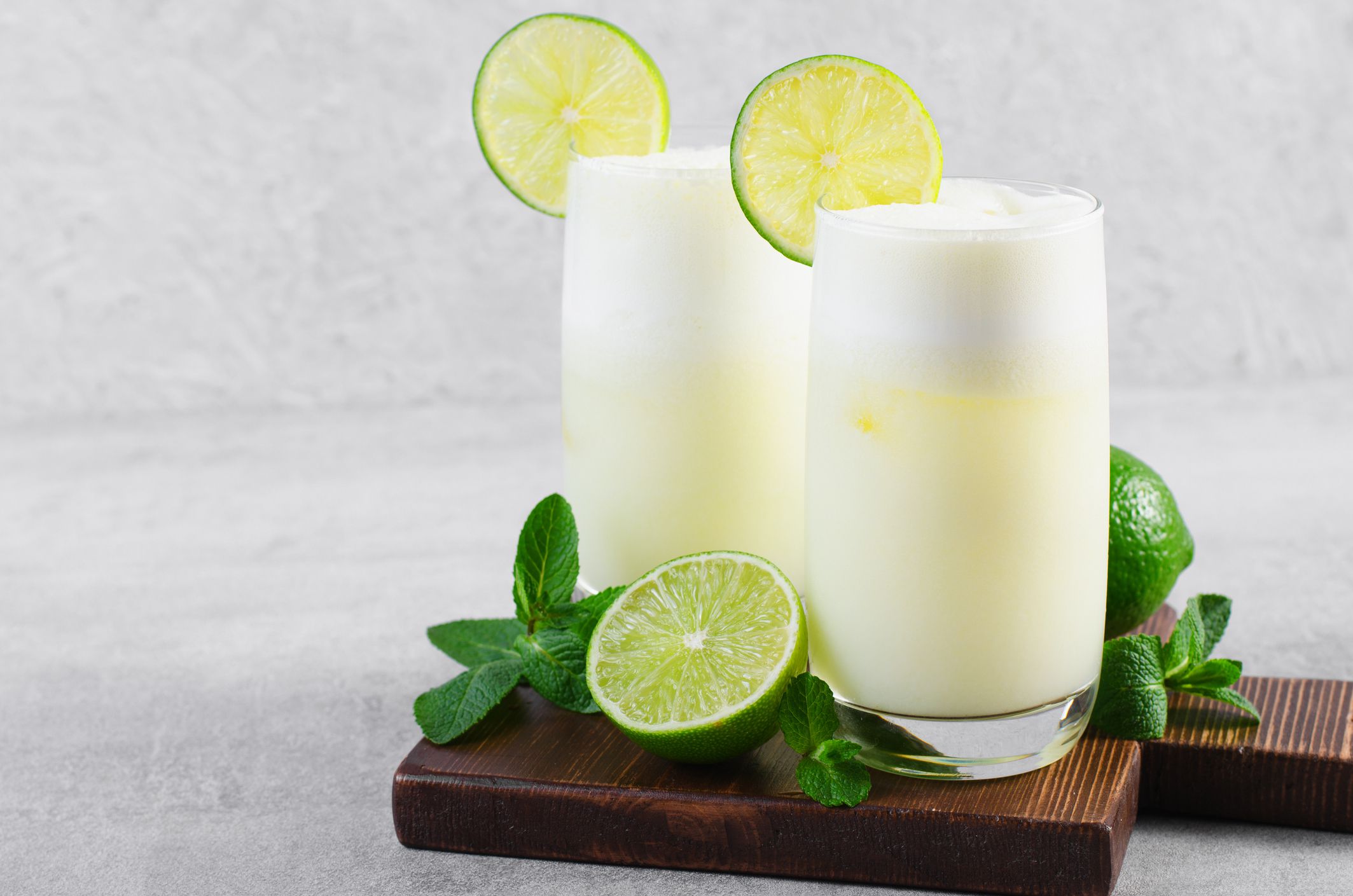 Brazilian Lemonade, Refreshing Creamy Lemonade or Limeade with Lime Slices and Mint on Bright Background