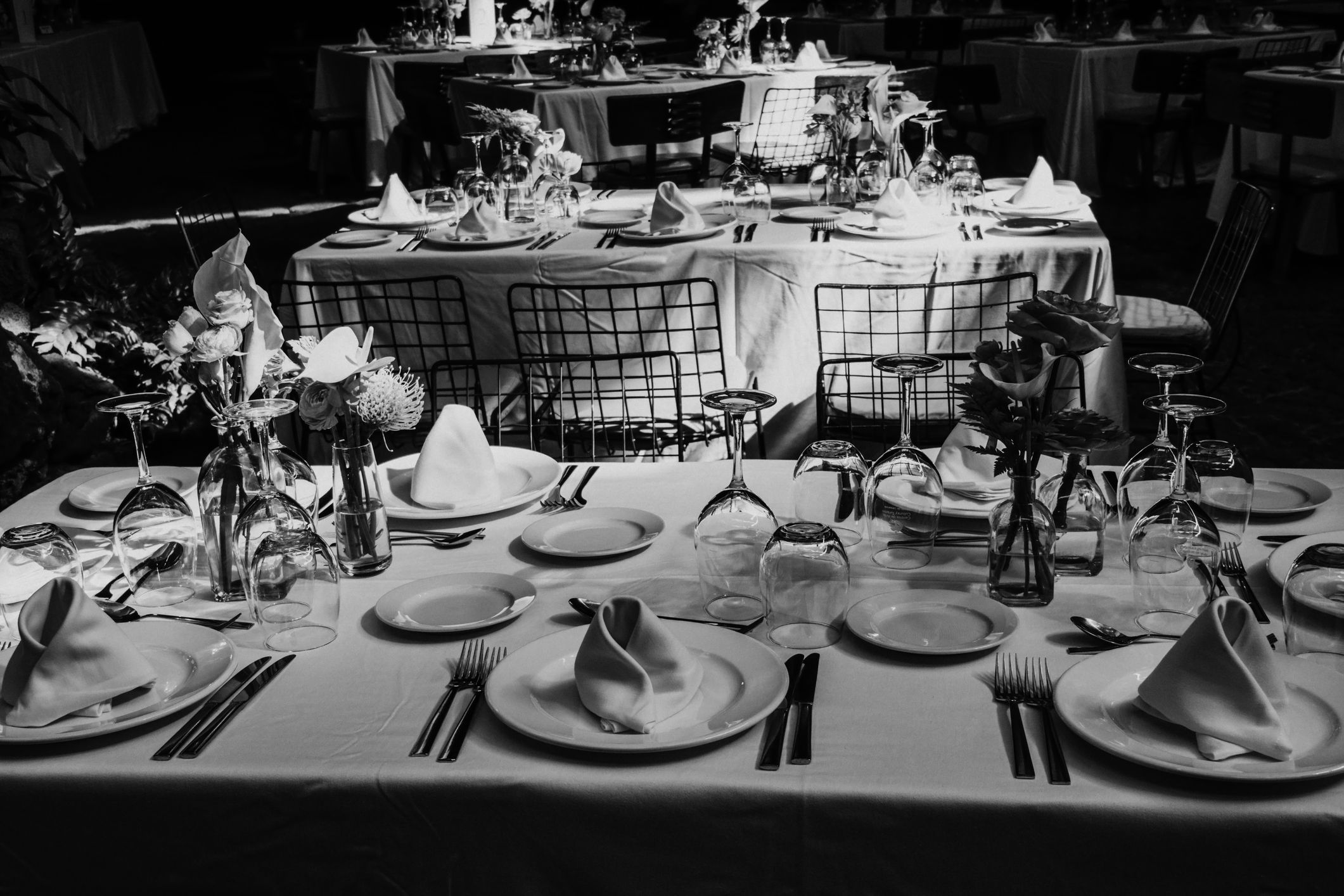 Beautifully laid tables with glasses, cutlery and crockery prepared for a great celebration. Black and white photography