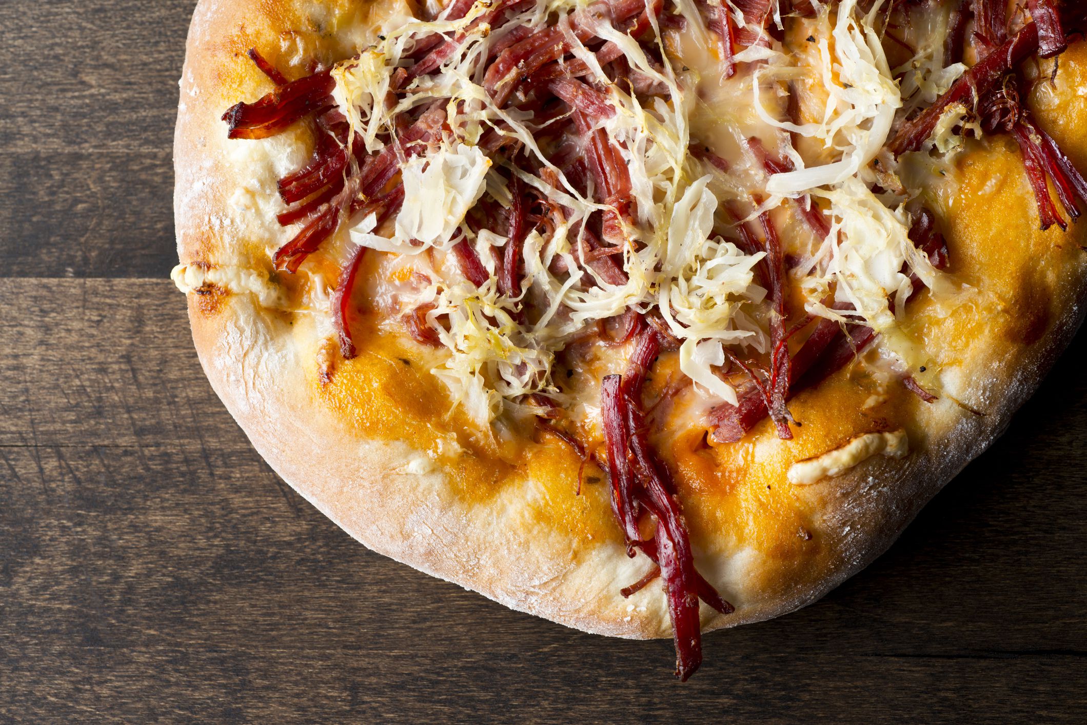 Reuben Pizza made of Corned Beef, Sauerkraut, Thousand Island Dressing and Swiss Cheese on Flatbread