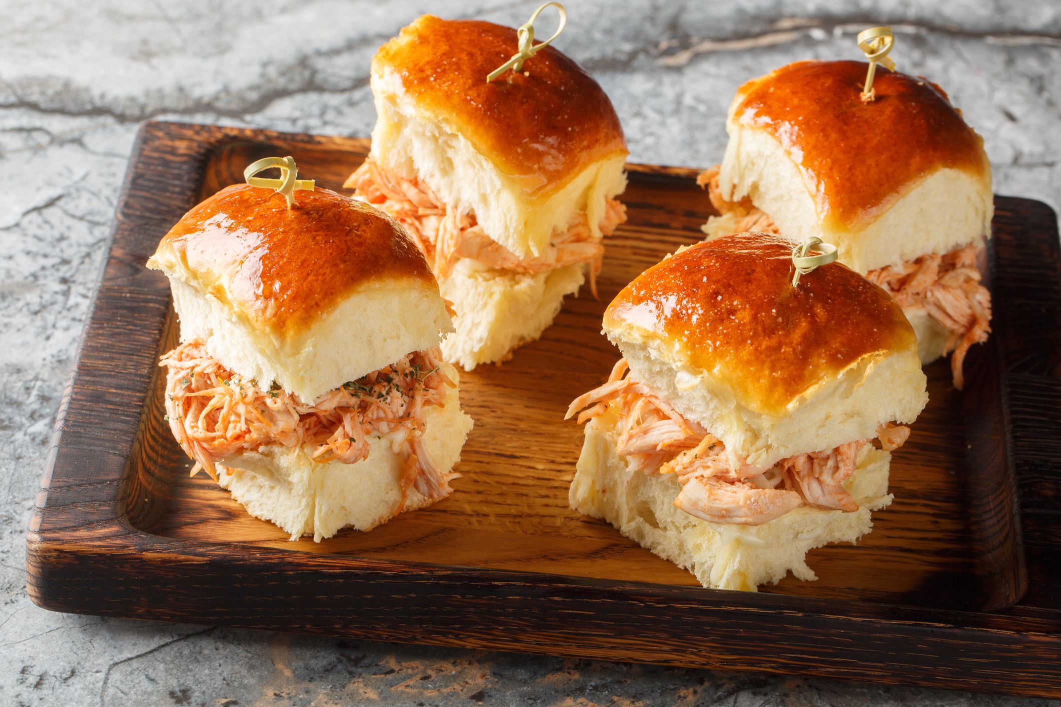 Chicken Cheese Sliders roll made with pulled chicken, tomato sauce, and Mozzarella closeup on the wooden board on the table. Horizontal