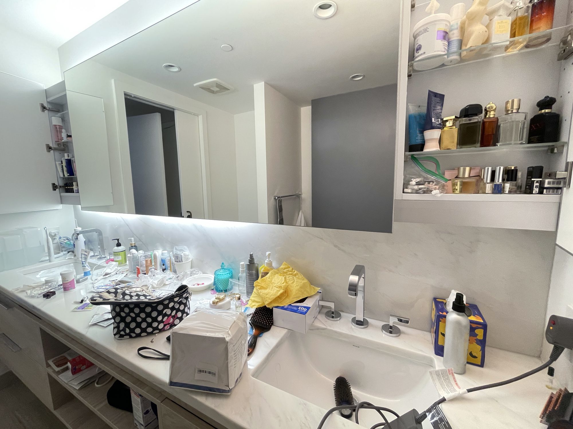 A young female's double sink cluttered bathroom in a fancy high- rise building in Los Angeles!