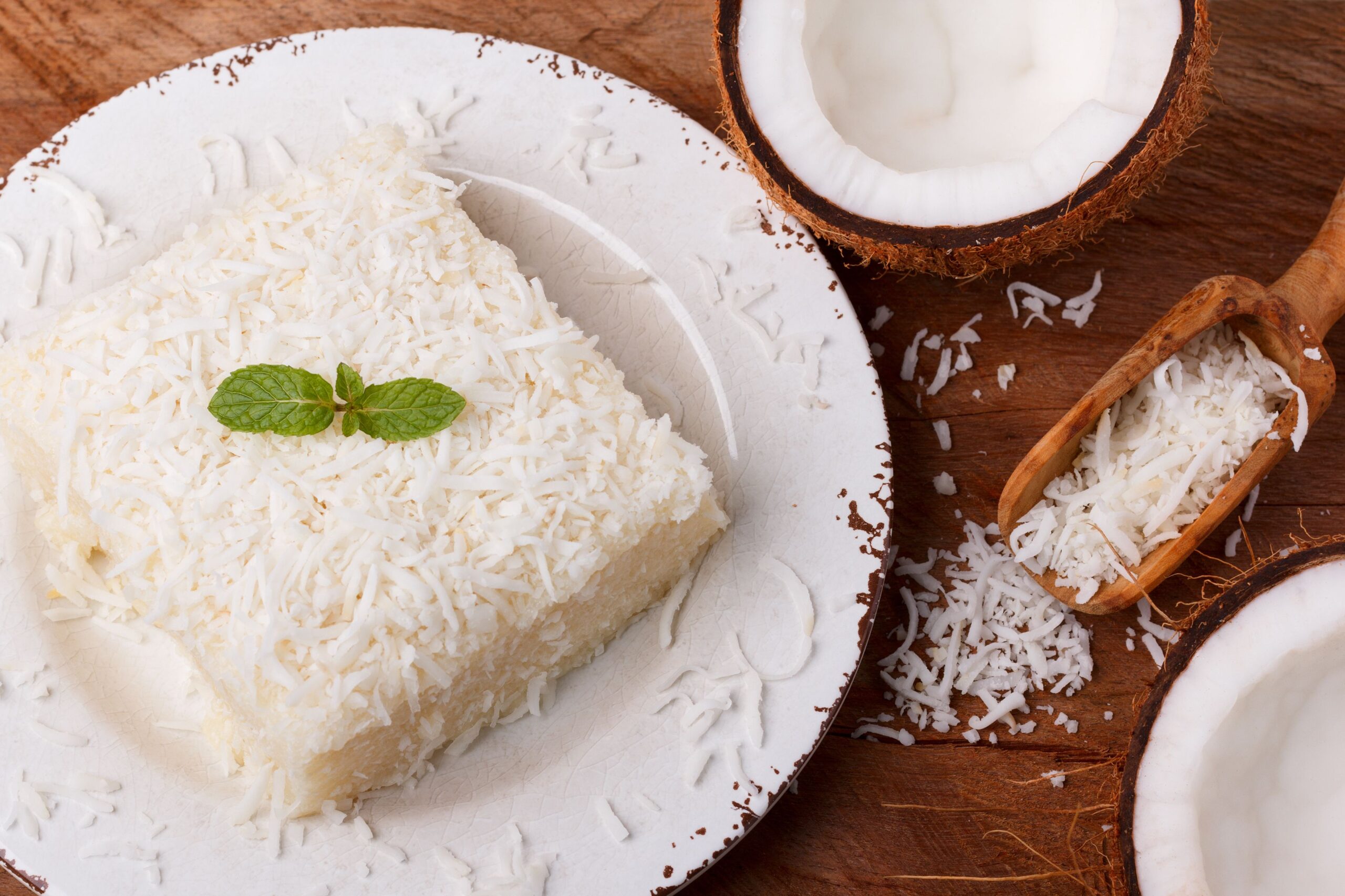 Brazilian traditional dessert: sweet couscous (tapioca) pudding (cuscuz doce) with coconut on plate on wooden background. Selective focus