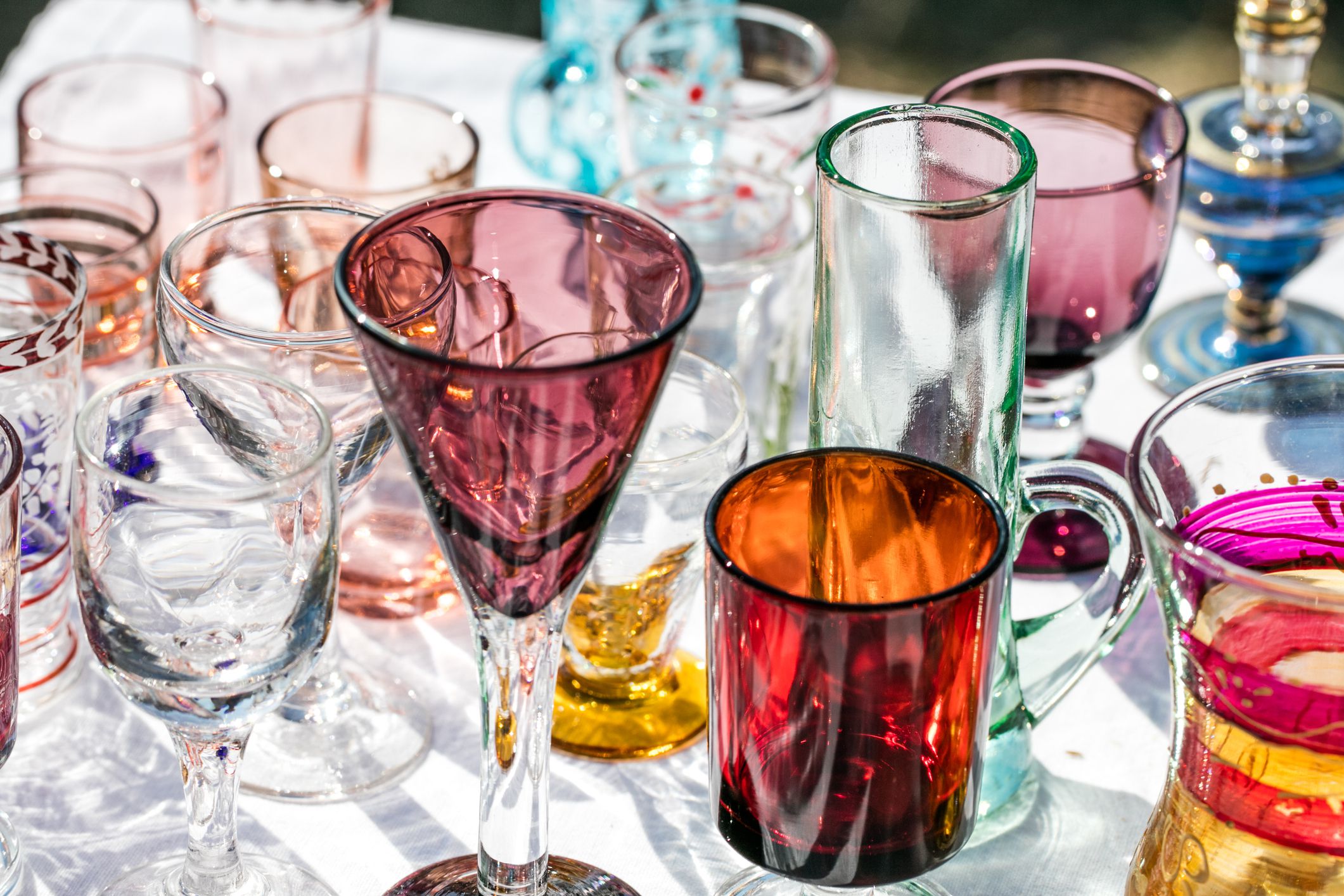 second hand beautiful glasses in different shapes and colors at outdoor flea market for collection or reusing dishes