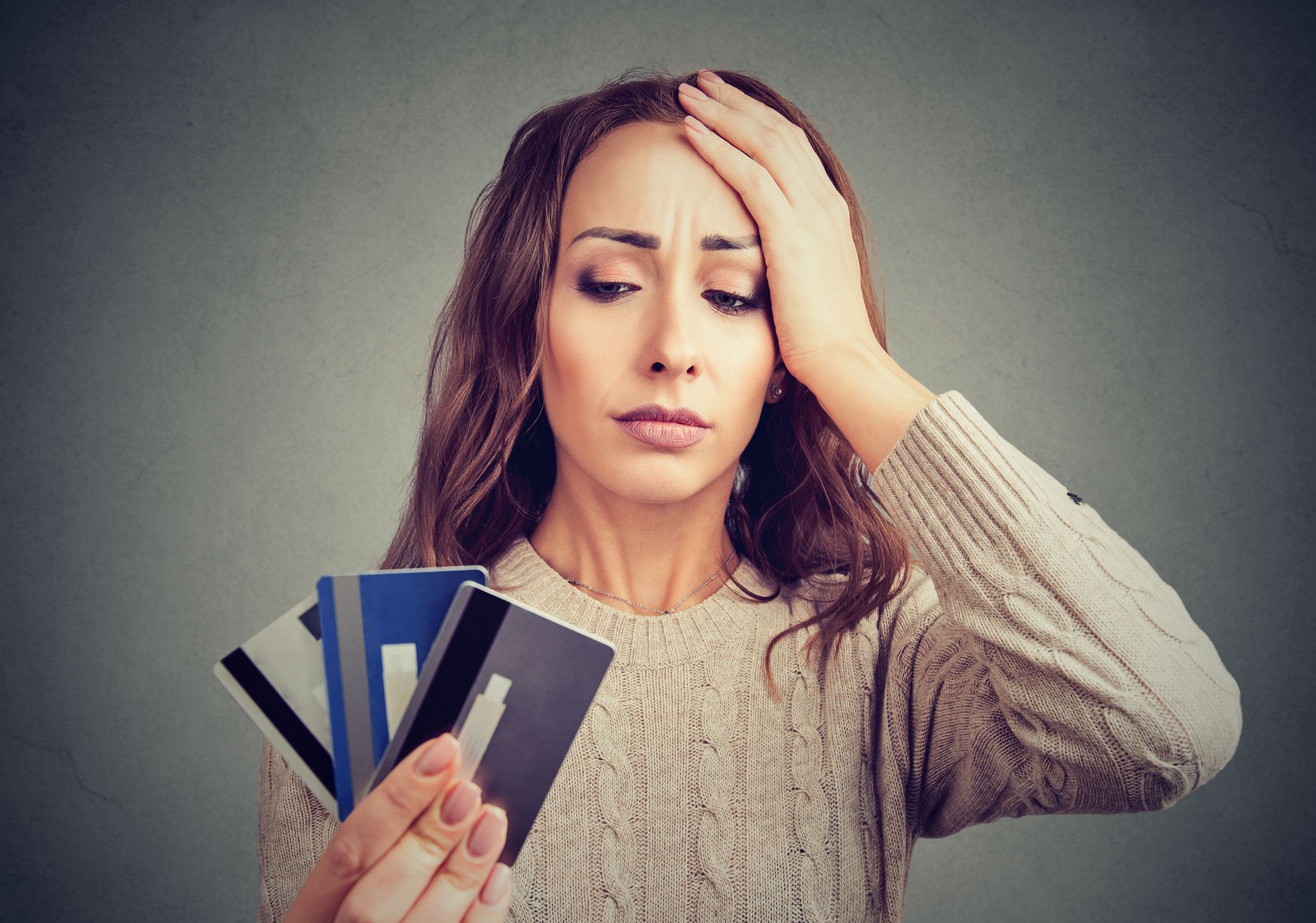 Young woman holding credit cards and looking stressed having financial problems.
