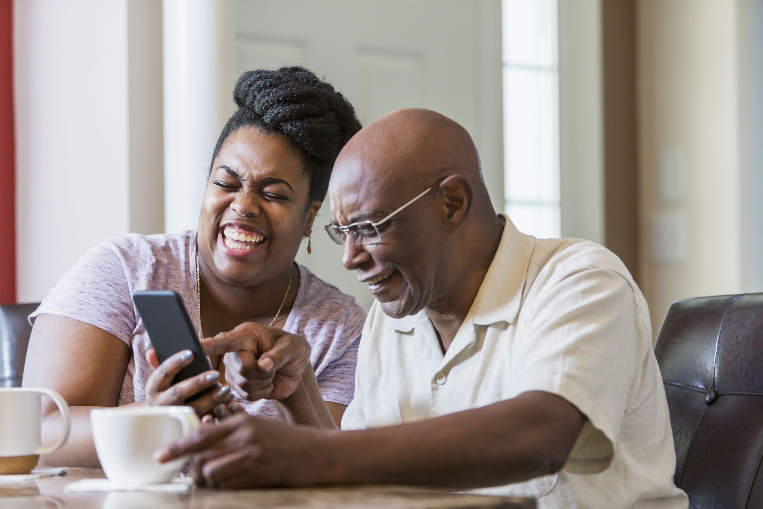 senior man with adult daughter using smart phone