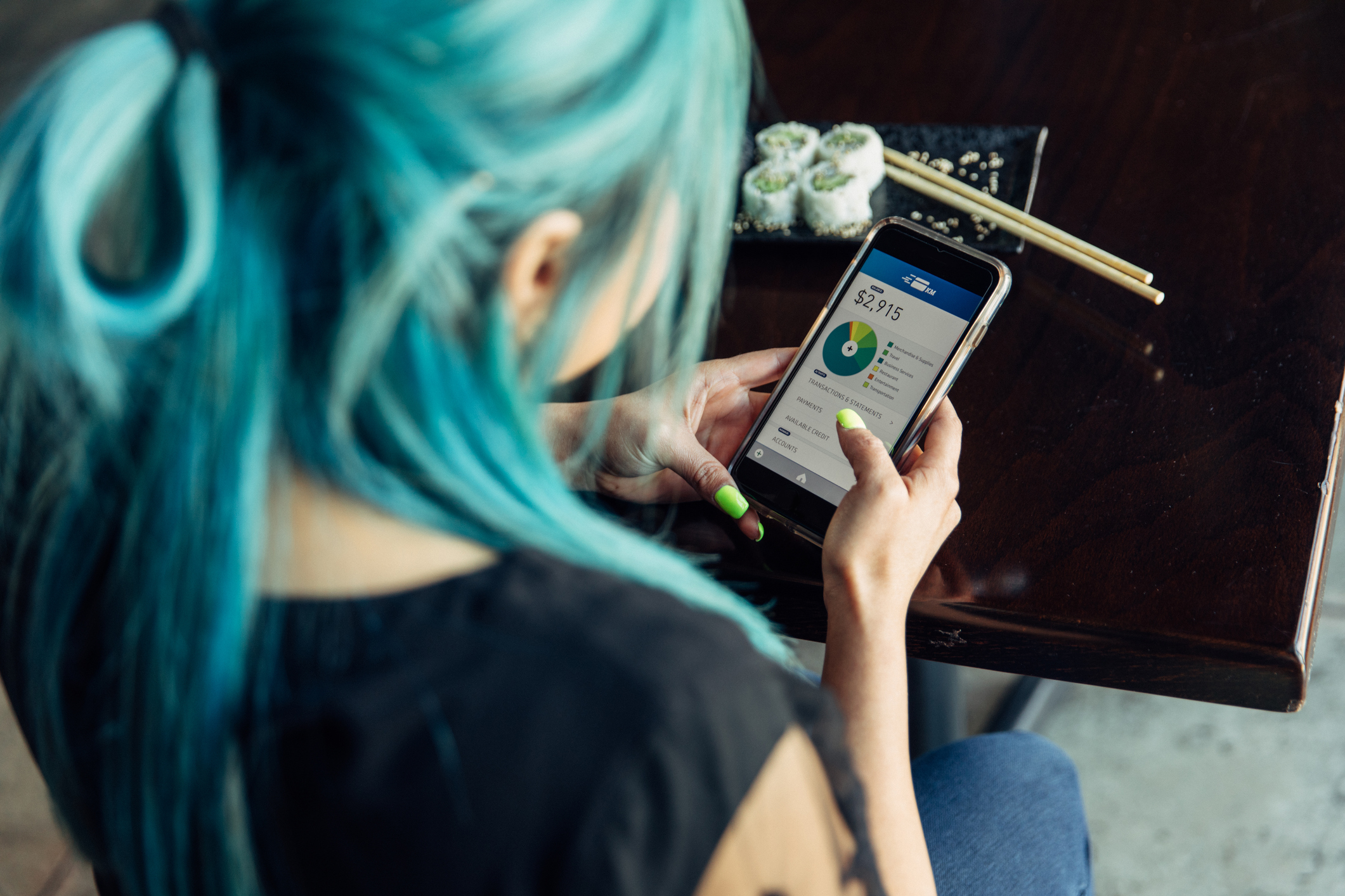 Top-Down View of a Hip Woman Checking Her Savings Account on an App on Her Smartphone