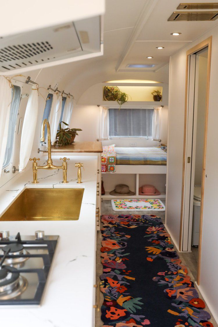 a floral rug facing a brass sink in an Airstream