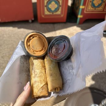 two spring rolls and a container of sauce