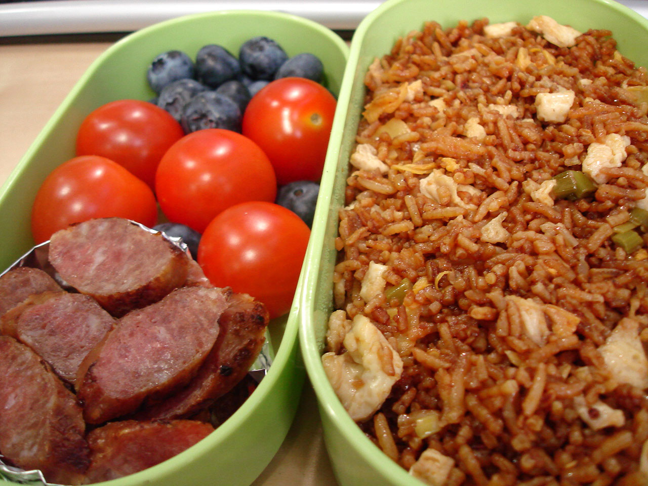 Closeup of a Bento Lunch, Sides of Sausage, Cherry Tomatoes, Blueberries, and Fried Rice