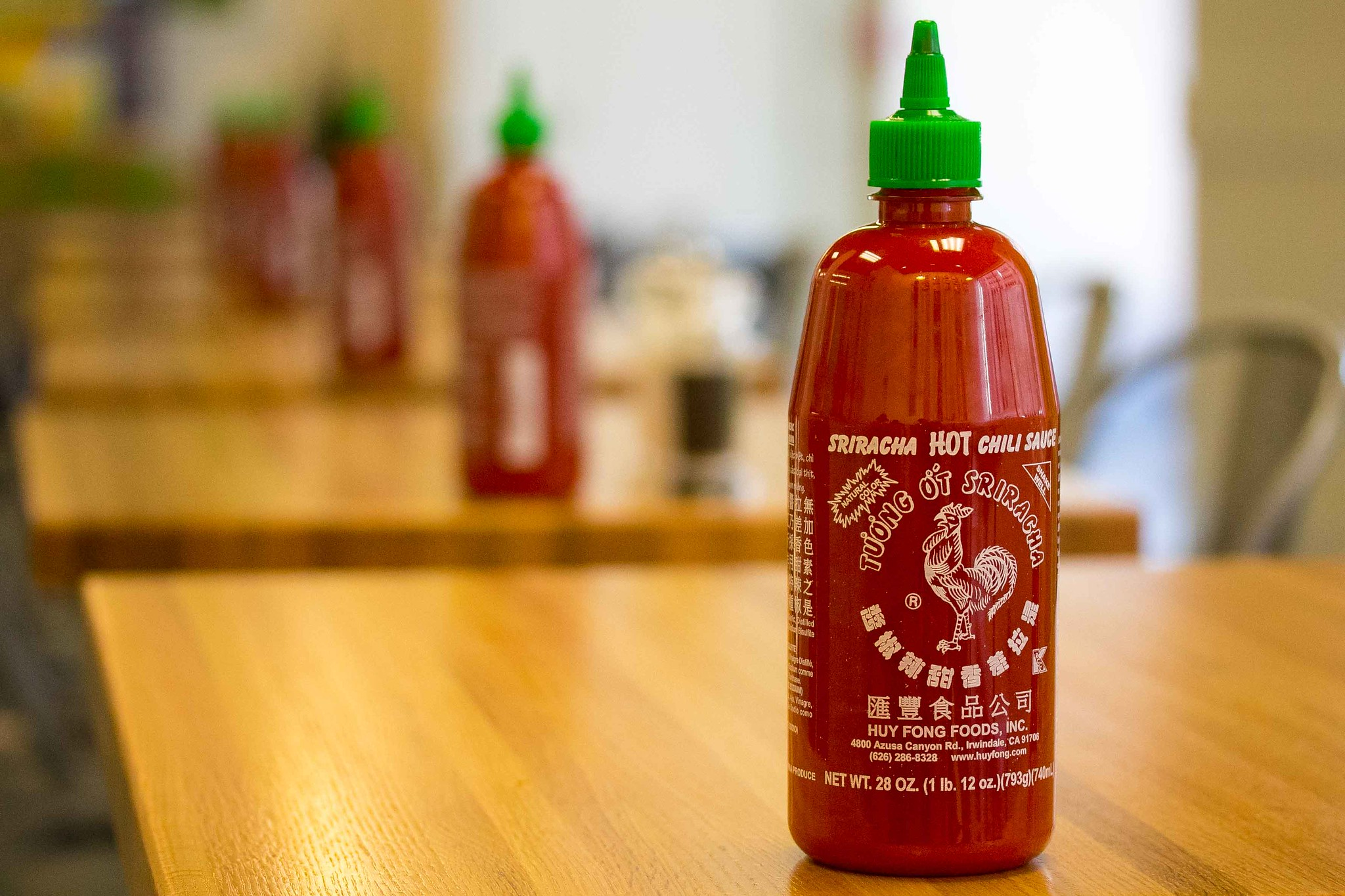 Rows of Sriracha Hot Sauce Bottles on Empty Tables in a Restaurant
