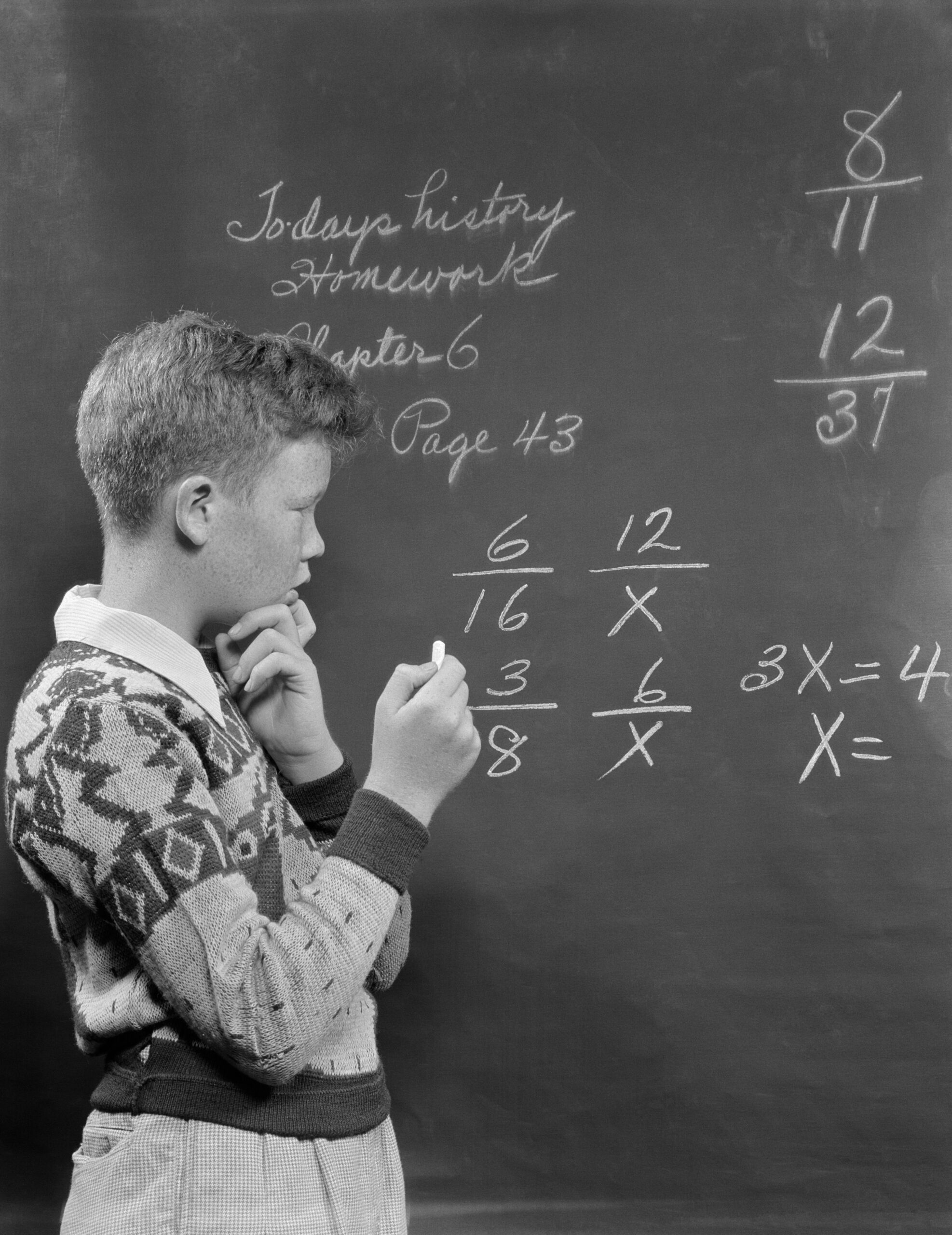 Young boy in the 1950s doing math at the chalkboard