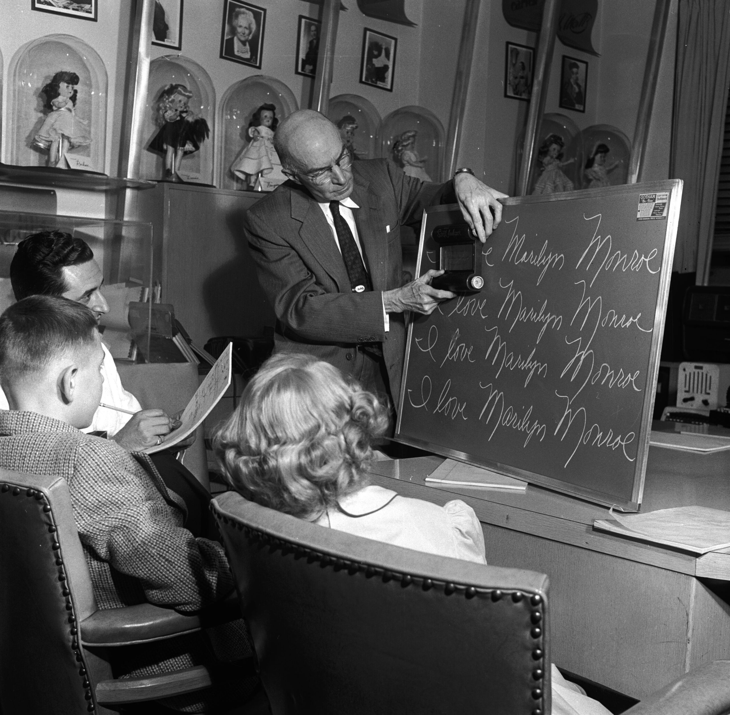 Teacher in the 1950s showing kids a chalkboard in cursive lesson
