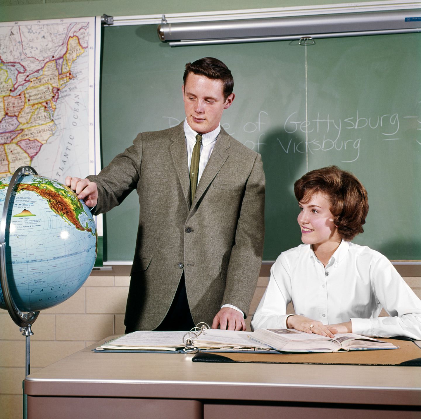 High school student pointing to the United States on a globe in the 60s