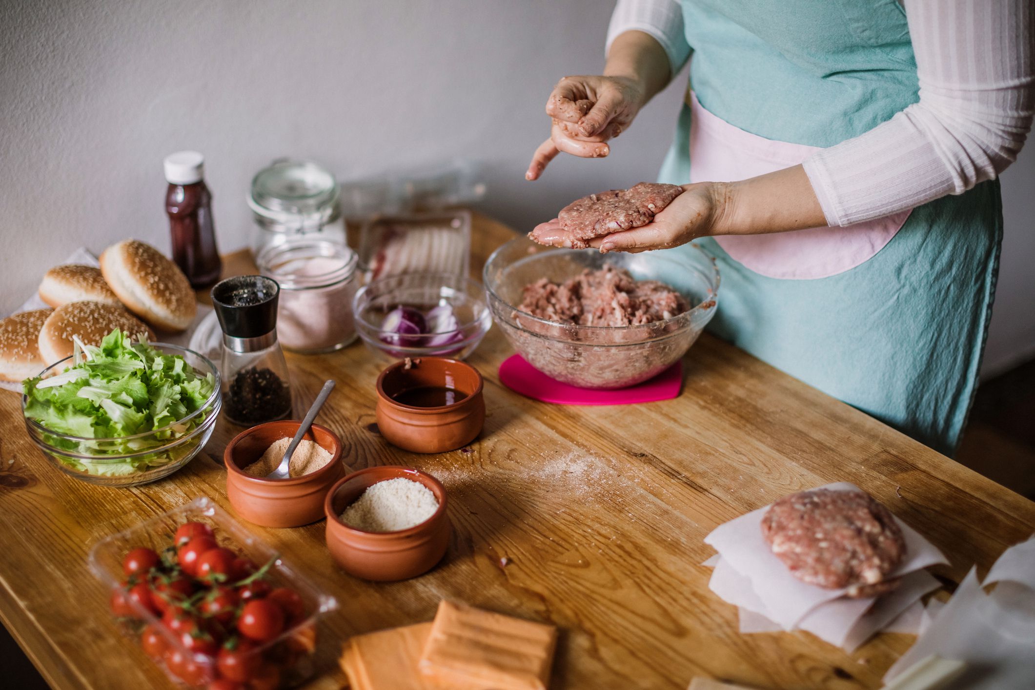 Young Woman Making Shapes Of Fresh Hamburgers